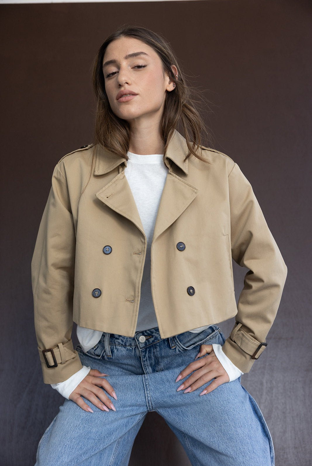 דוגמנית לובשת ג'קט קצר בז' אופנתי עם כפתורים, חולצה לבנה וג'ינס רחב לנשים