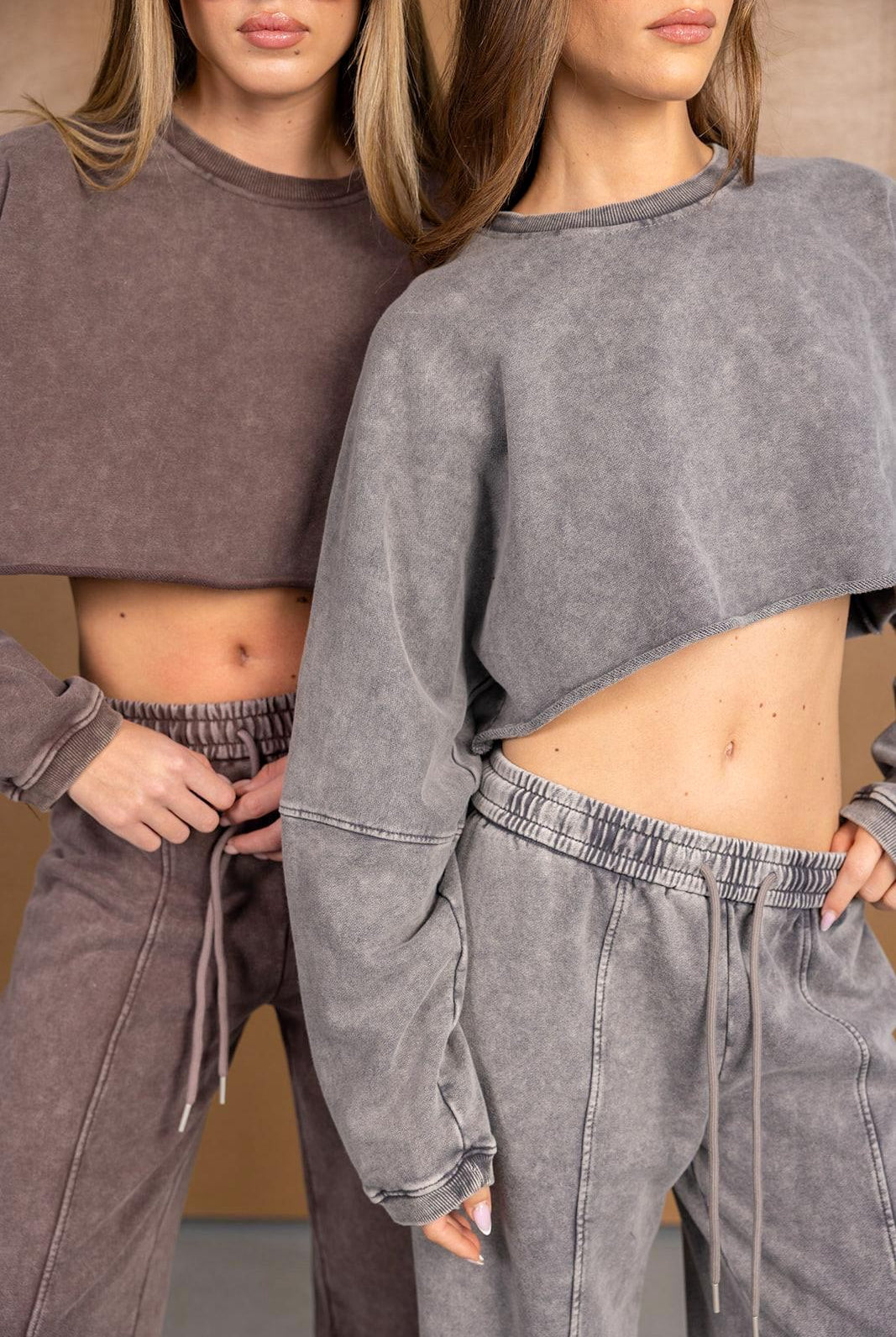 שתי נשים לובשות סט טרנינג אופנתי בצבעי חום ואפור, חולצות קרופ ומכנסיים בגזרה גבוהה.