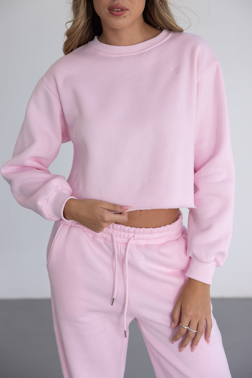 אישה לובשת סט טרנינג ורוד בהיר אופנתי לנשים, סווטשירט קצר ומכנסיים ארוכים