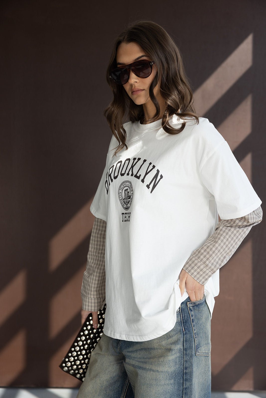 אופנת נשים, דוגמנית עם חולצת טי שירט BROOKLYN לבנה, ג'ינס משופשף ומשקפי שמש