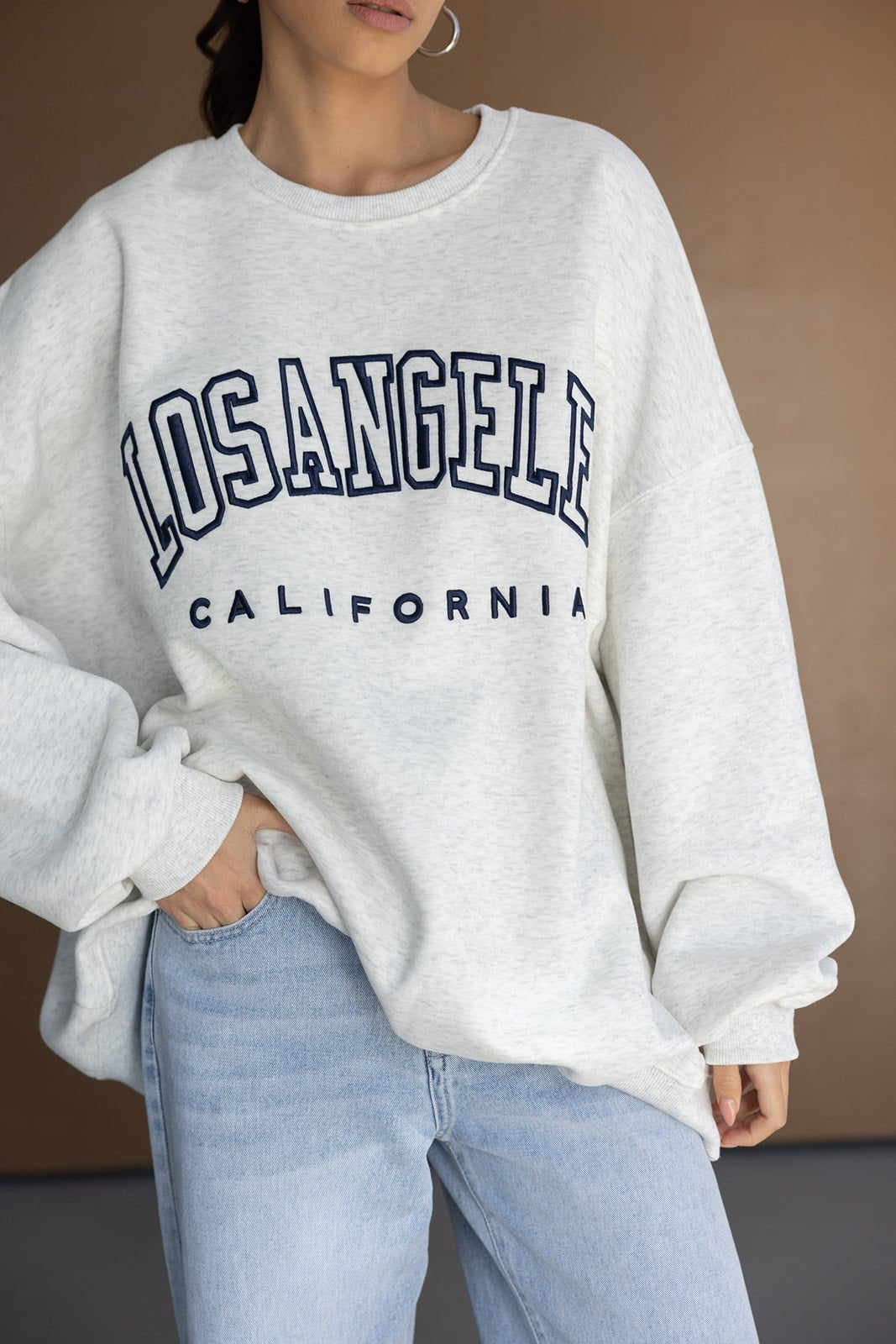 סווטשירט נשים אפור עם כיתוב LOS ANGELES CALIFORNIA בגזרה רחבה, משולב עם ג'ינס בהיר