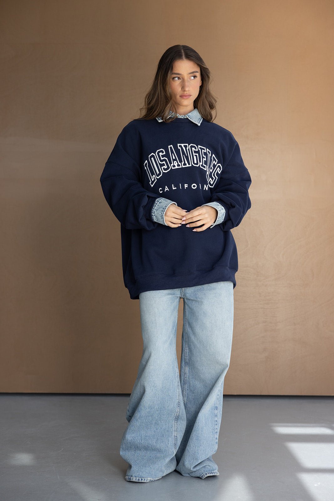דוגמנית לובשת סווטשירט כחול עם כיתוב 'LOS ANGELES', ג'ינס רחב, לוק אופנתי לנשים