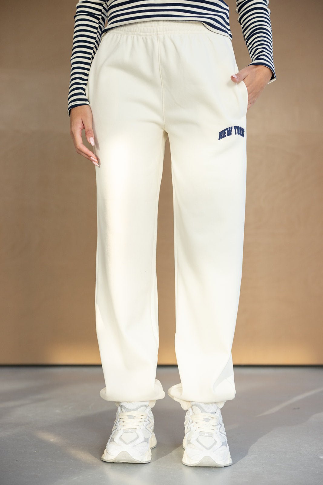 מכנסי טרנינג לבנים לנשים עם כיתוב ניו יורק, חולצת פסים ונעלי ספורט אופנתיות