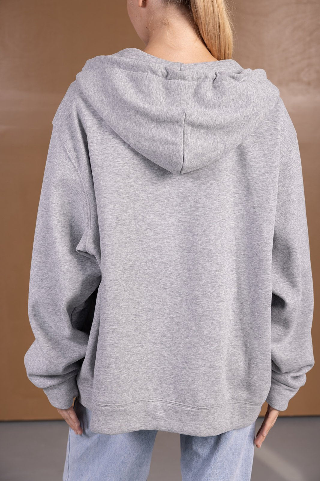 אישה בחולצת קפוצ׳ון אפורה רחבה, מבט מהגב, אופנת נשים ונערות