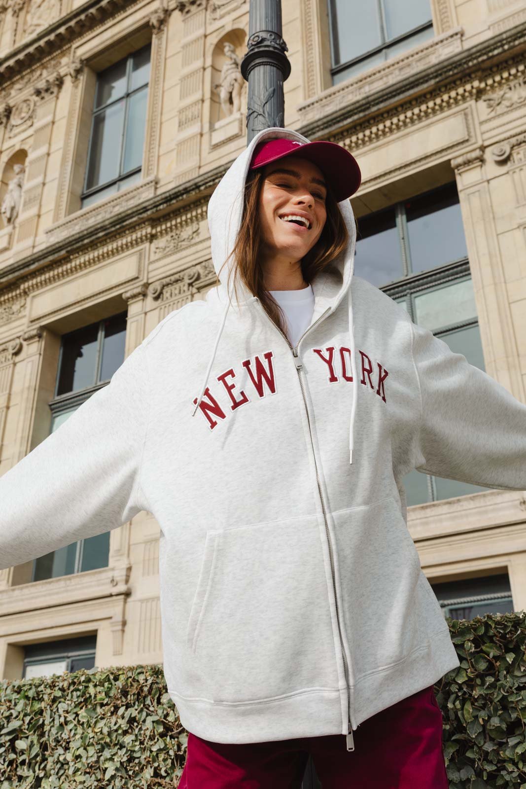 אישה צעירה עם קפוצ'ון אפור וכיתוב NEW YORK וכובע בורדו, אופנת רחוב לנשים