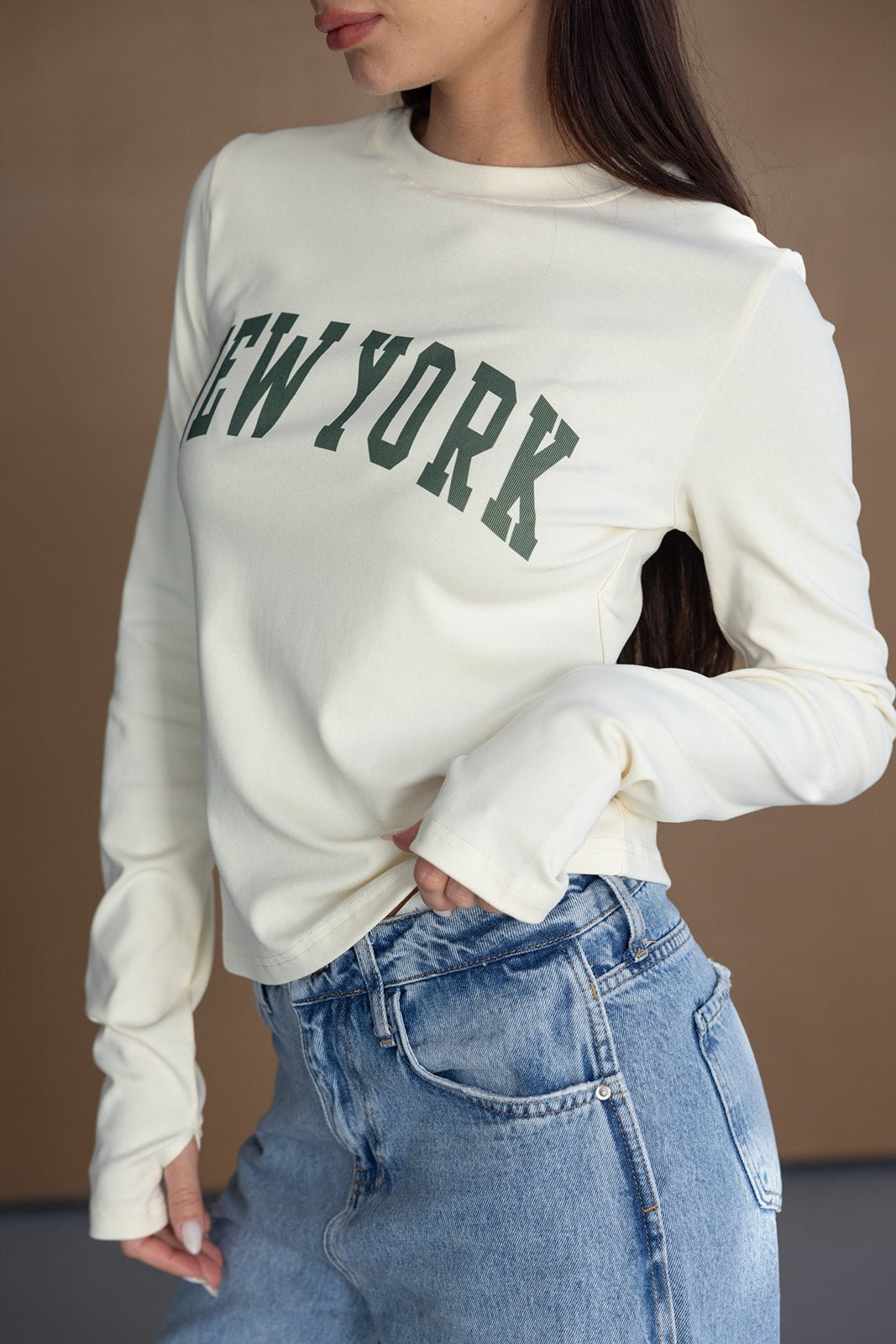 חולצת שרוולים ארוכים בגוון שמנת עם כיתוב NEW YORK, משולבת עם ג'ינס אופנתי לנשים