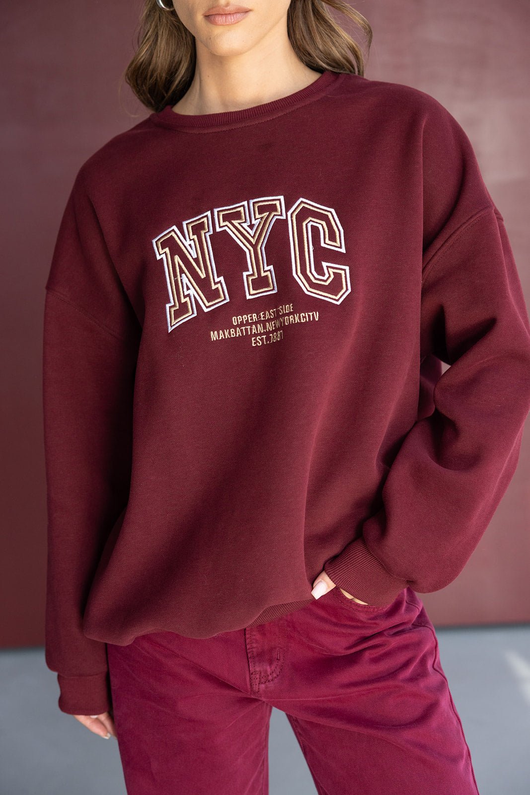 אישה לובשת סווטשירט בורדו עם הדפס NYC ומכנסיים תואמים, אופנת חורף קז'ואל לנשים