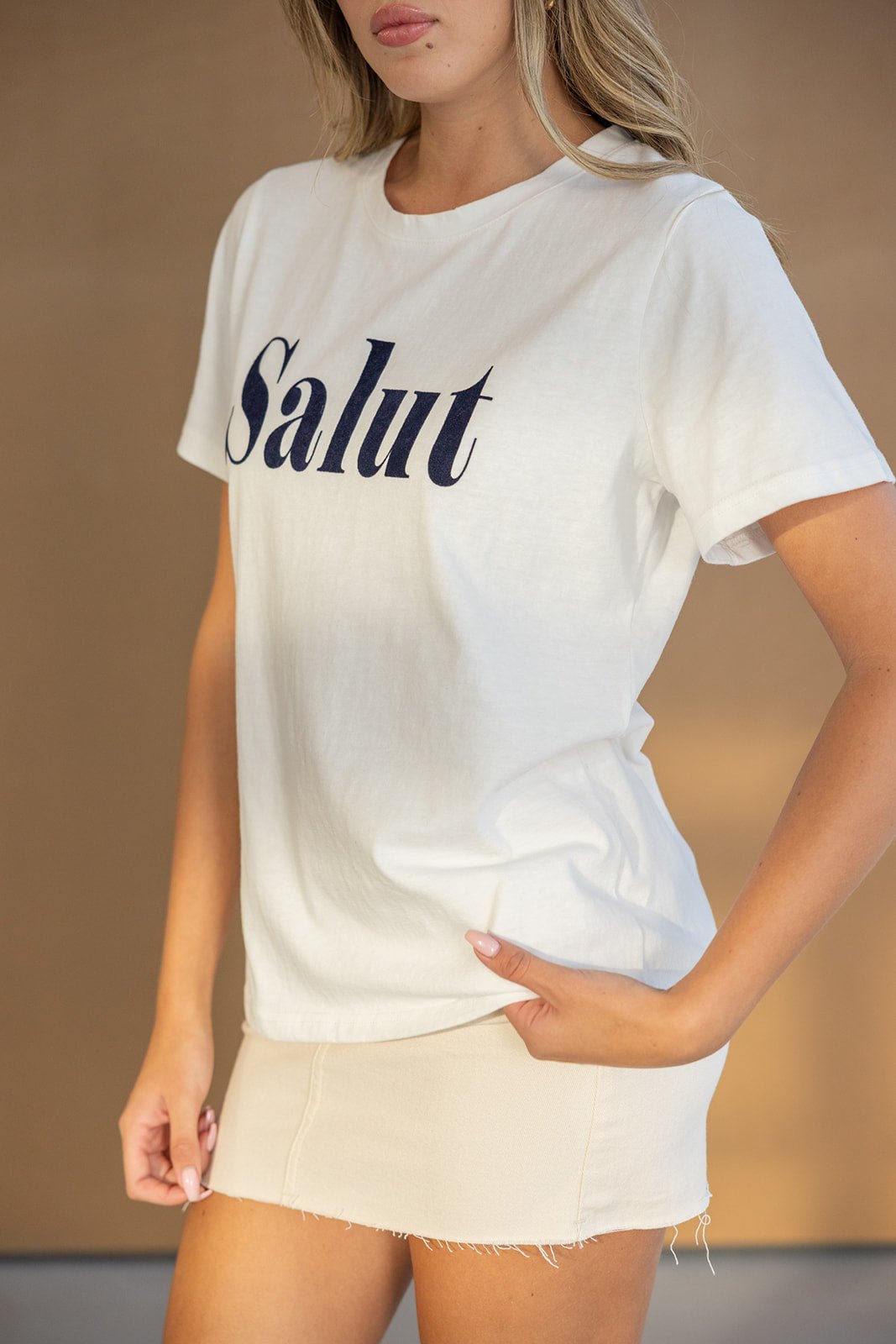 חולצת טי לבנה עם כיתוב Salut בשחור, חצאית מיני בז', אופנת קיץ לנשים