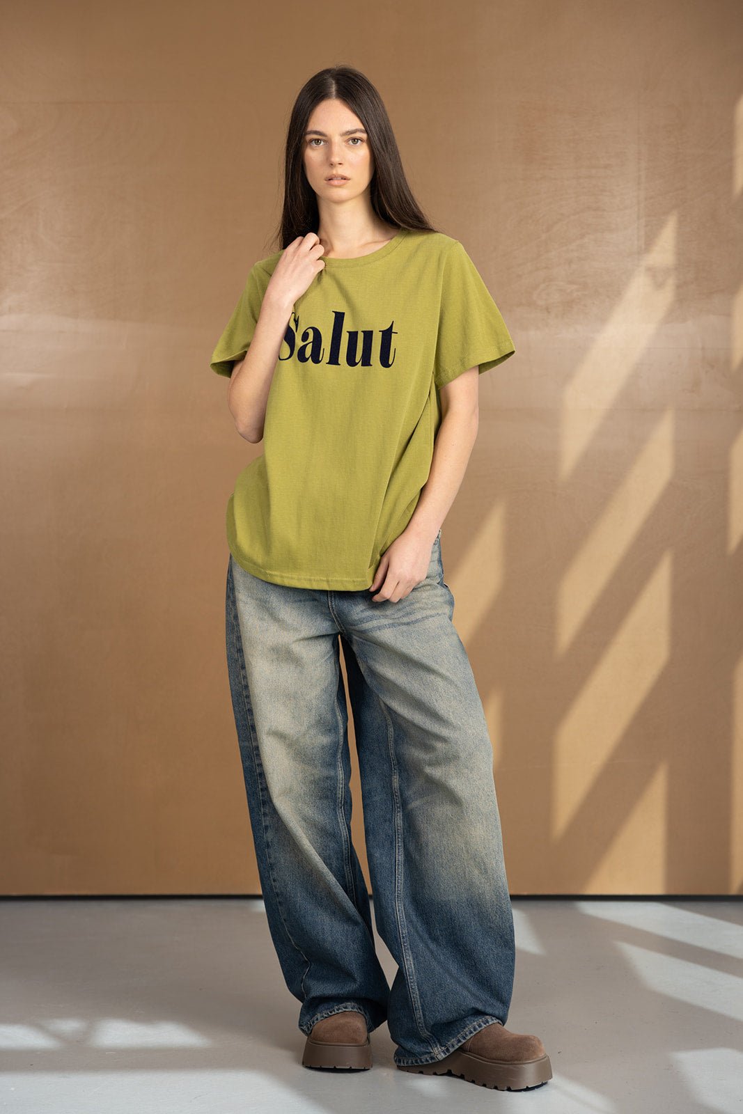 דוגמנית לובשת חולצת טי ירוקה עם הדפס Salut ומכנסי ג’ינס רחבים, אופנת נשים עדכנית