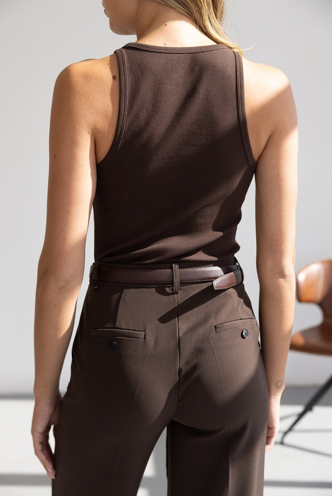 אישה לובשת גופיית בייסיק חומה ומכנסיים מחויטים חומים, אופנת נשים קיץ