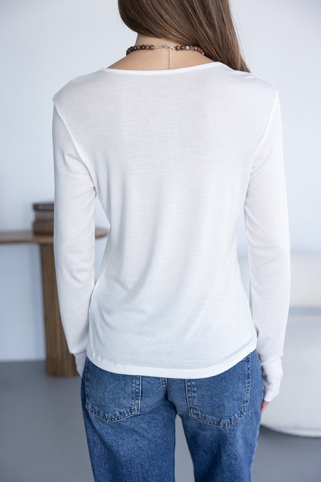 חולצת בסיס לבנה ארוכה לנשים, גזרה ישרה, נלבשת עם ג'ינס בגזרה גבוהה, צילום גב