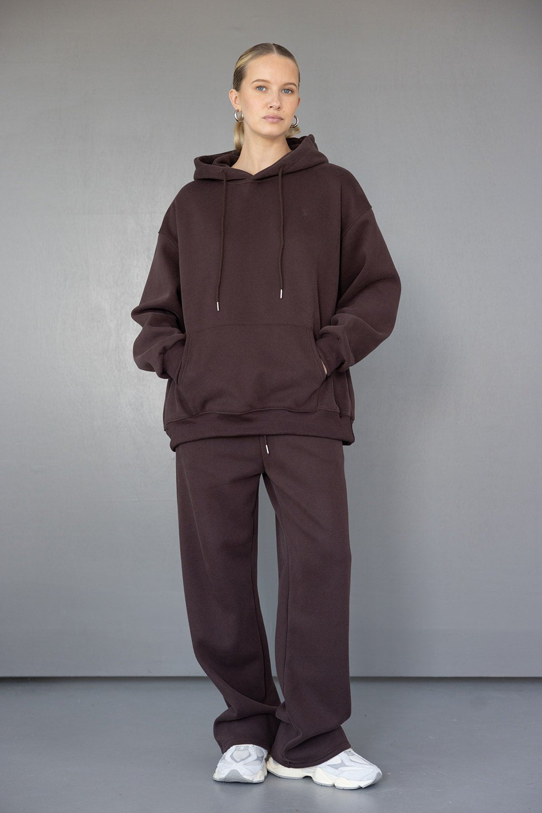 אישה לובשת סט קפוצ'ון ומכנסיים חומים רחבים עם נעלי סניקרס לבנות, אופנת חורף לנשים