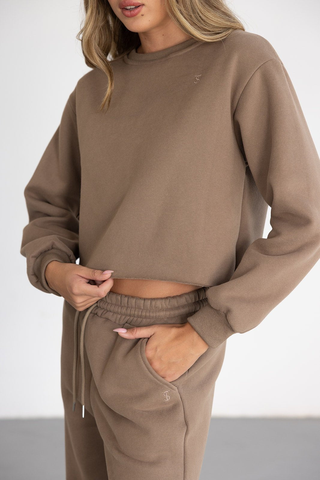 דוגמנית לובשת סט טרנינג נשים בגוון חום, חולצה עם שרוולים ארוכים ומכנסיים עם גומי.