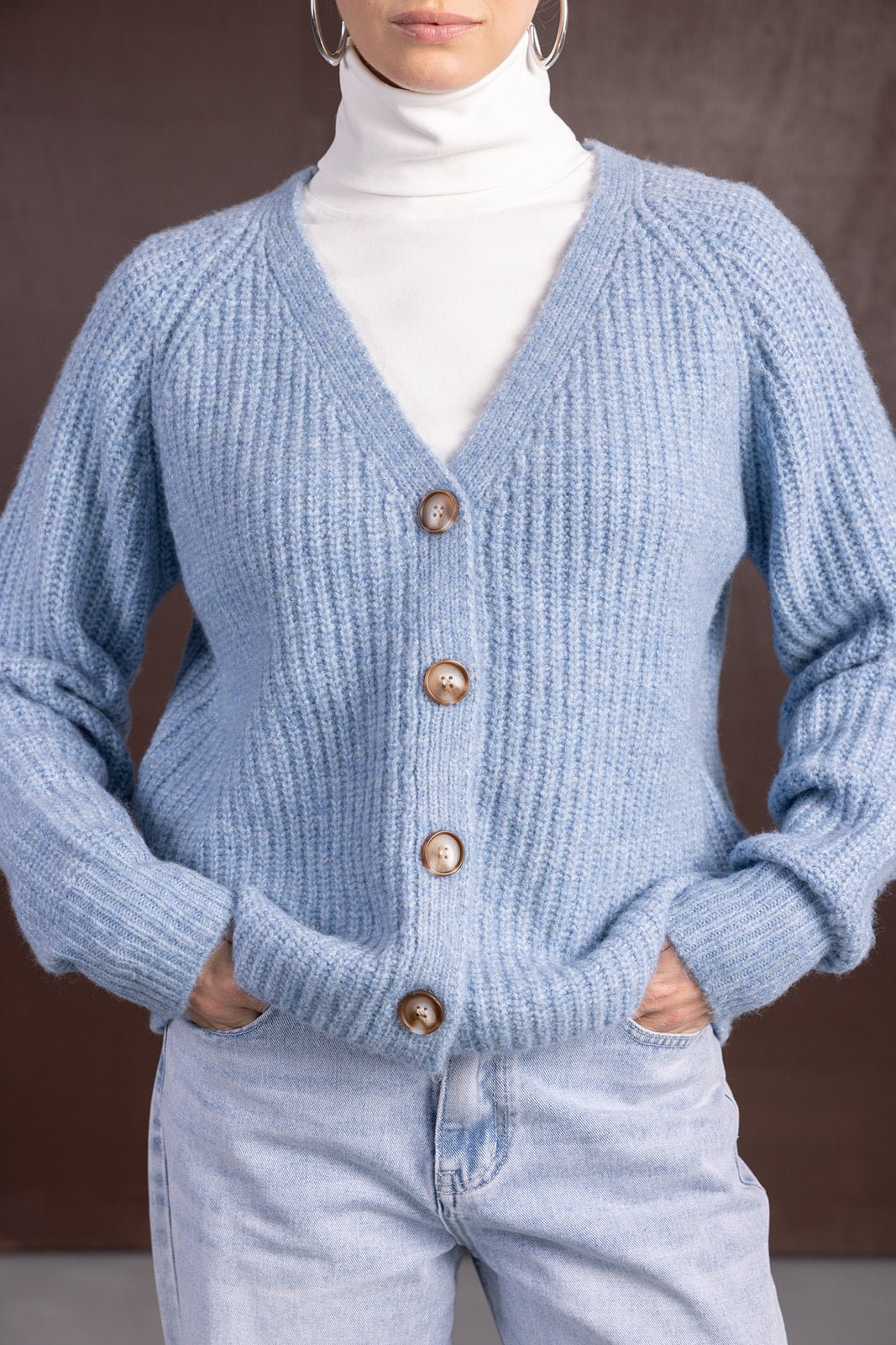 קרדיגן סרוג לנשים בצבע תכלת עם כפתורים, על חולצת גולף לבנה ומכנסי ג'ינס בהירים