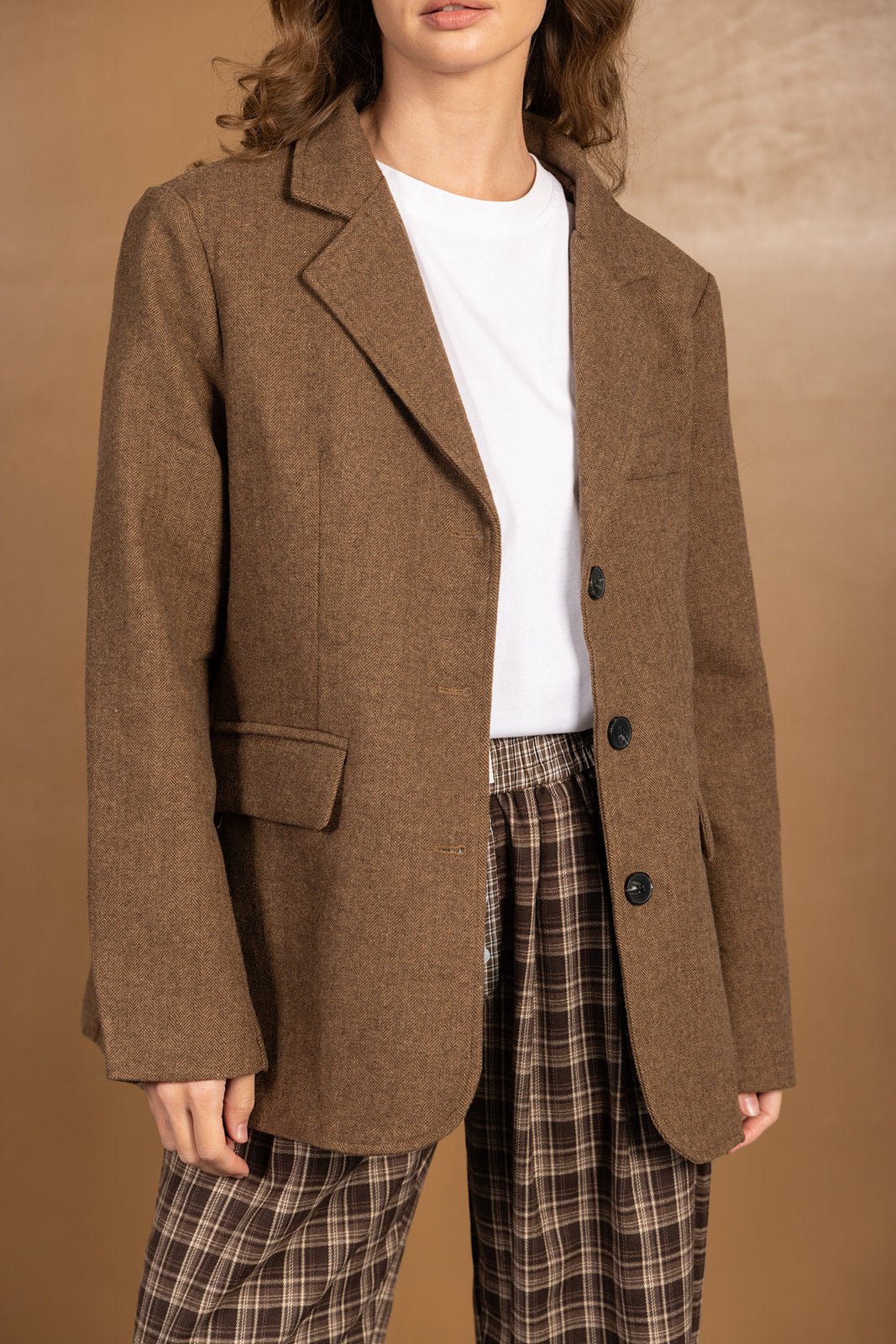 בלייזר חום לנשים עם כפתורים שחורים, חולצה לבנה ומכנס משובץ חום, מראה אלגנטי וטרנדי