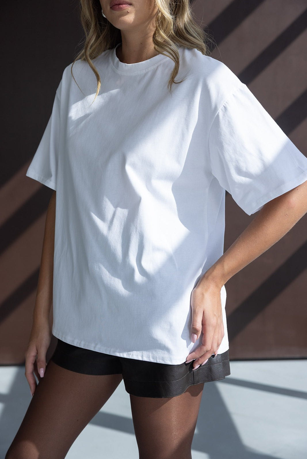 אישה לובשת חולצת טי לבנה ומכנסיים קצרים שחורים, אופנת קיץ לנשים צעירות