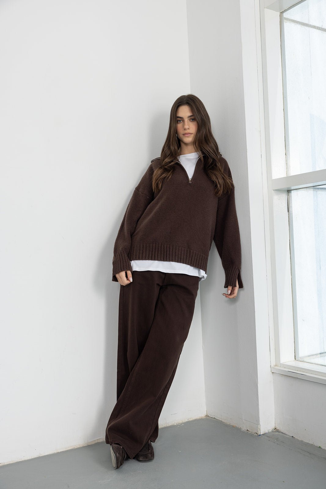 דוגמנית לובשת סוודר חום עם רוכסן ומכנסיים רחבים חומים, אופנה נשית לעונת החורף