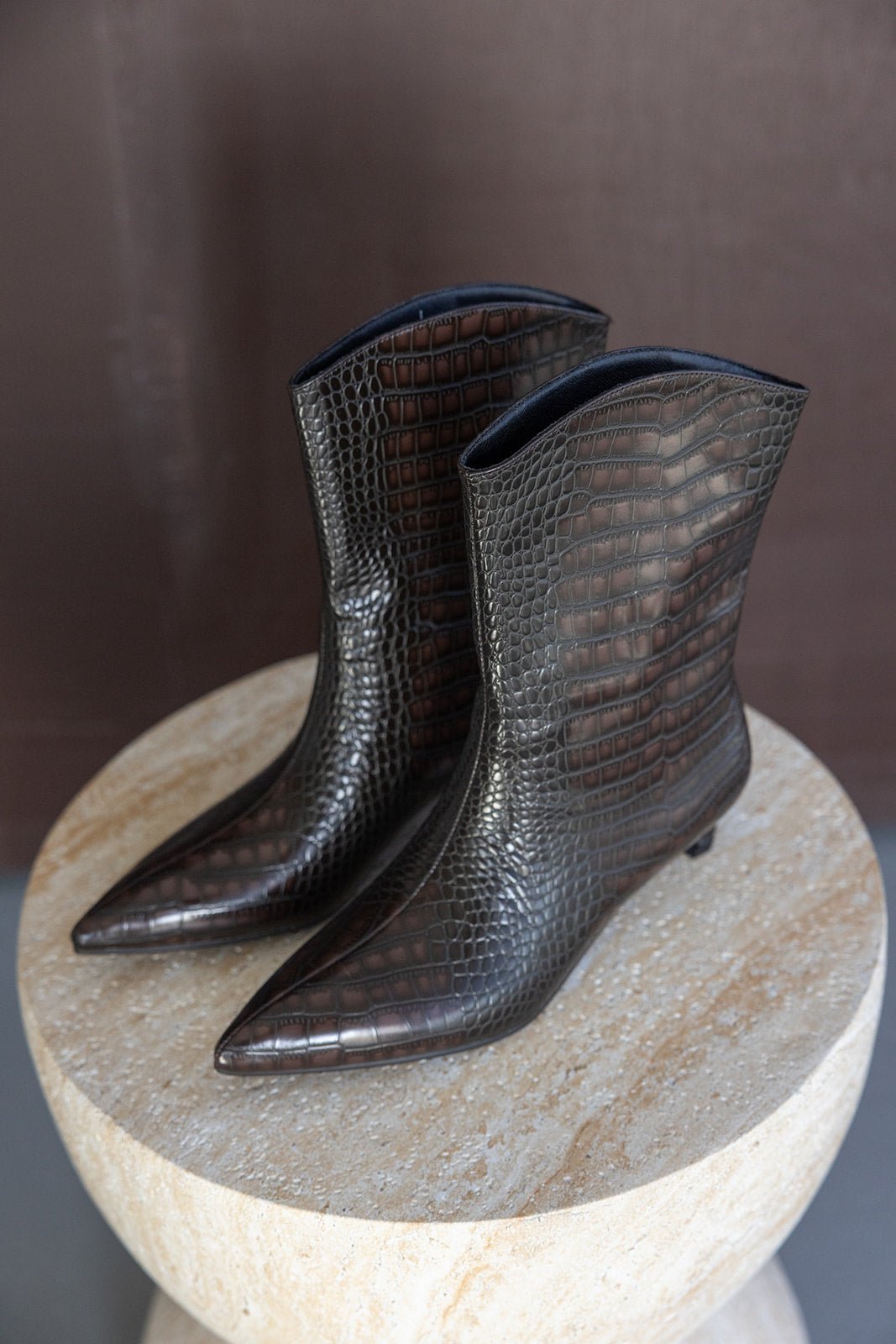 מגפי נשים מעור דמוי קרוקודיל חום, עקב נמוך, חוד מחודד, על שולחן עגול