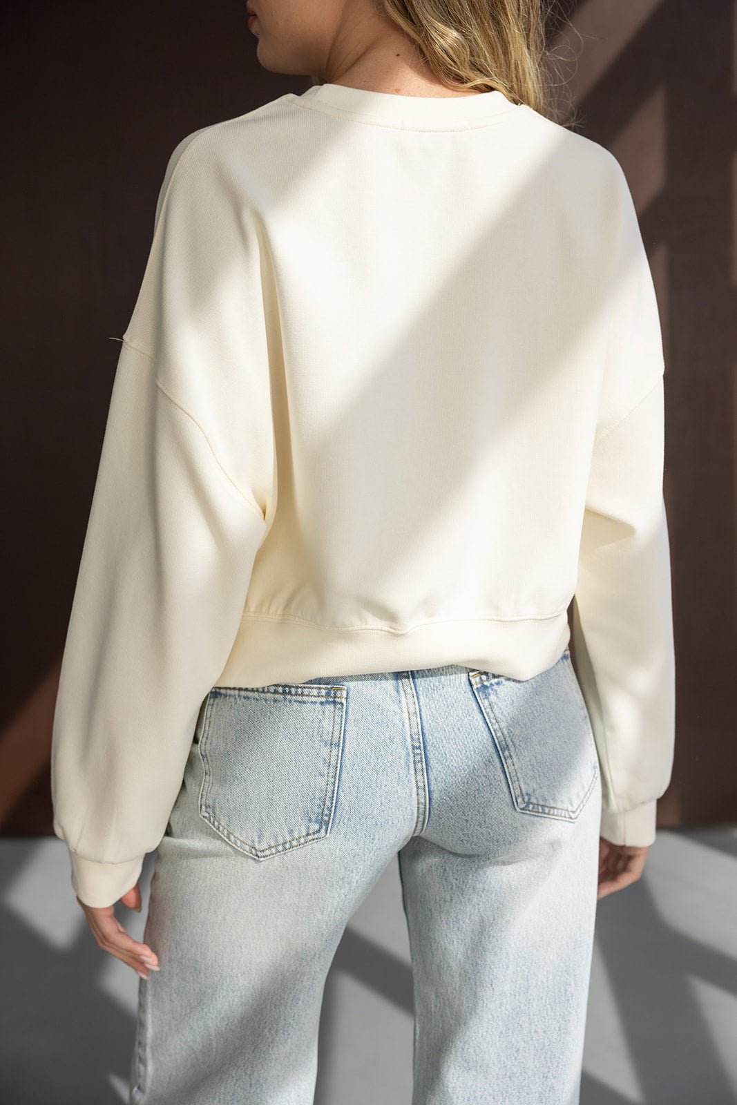 חולצת סווטשירט בז' לנשים עם שרוולים ארוכים בשילוב מכנסי ג'ינס בהירים אופנתיים