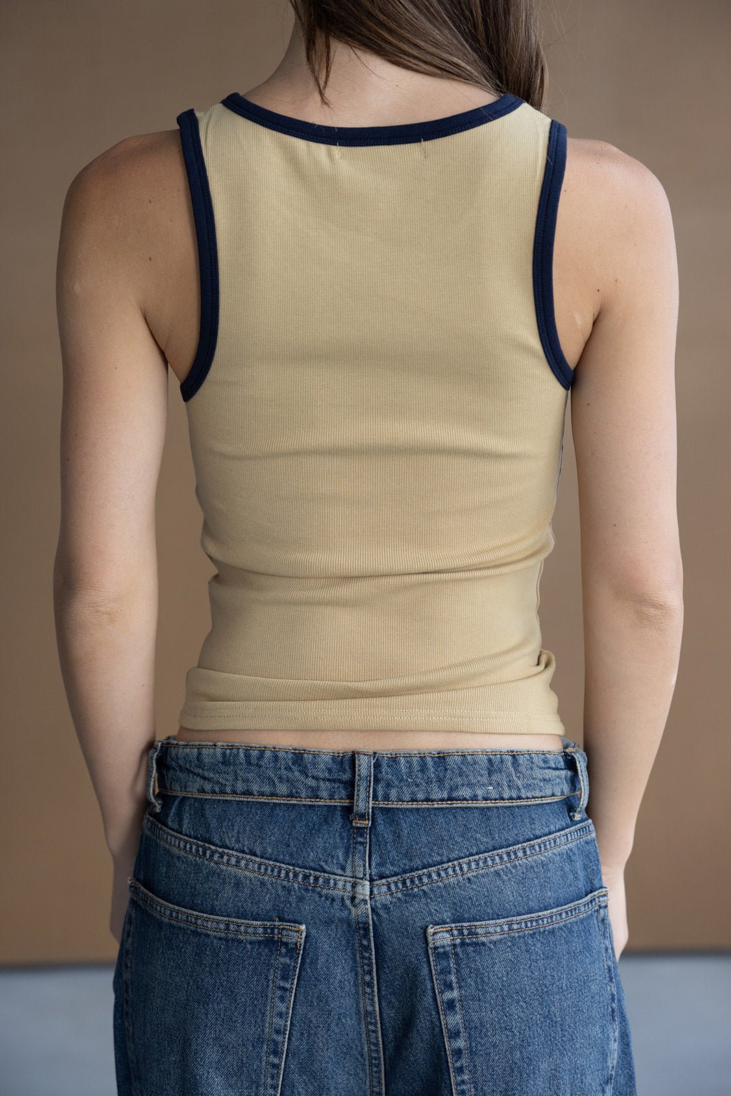 גופיית נשים בגוון בז' עם שוליים כהים, משולבת עם ג'ינס כחול, מוצגת על דוגמנית