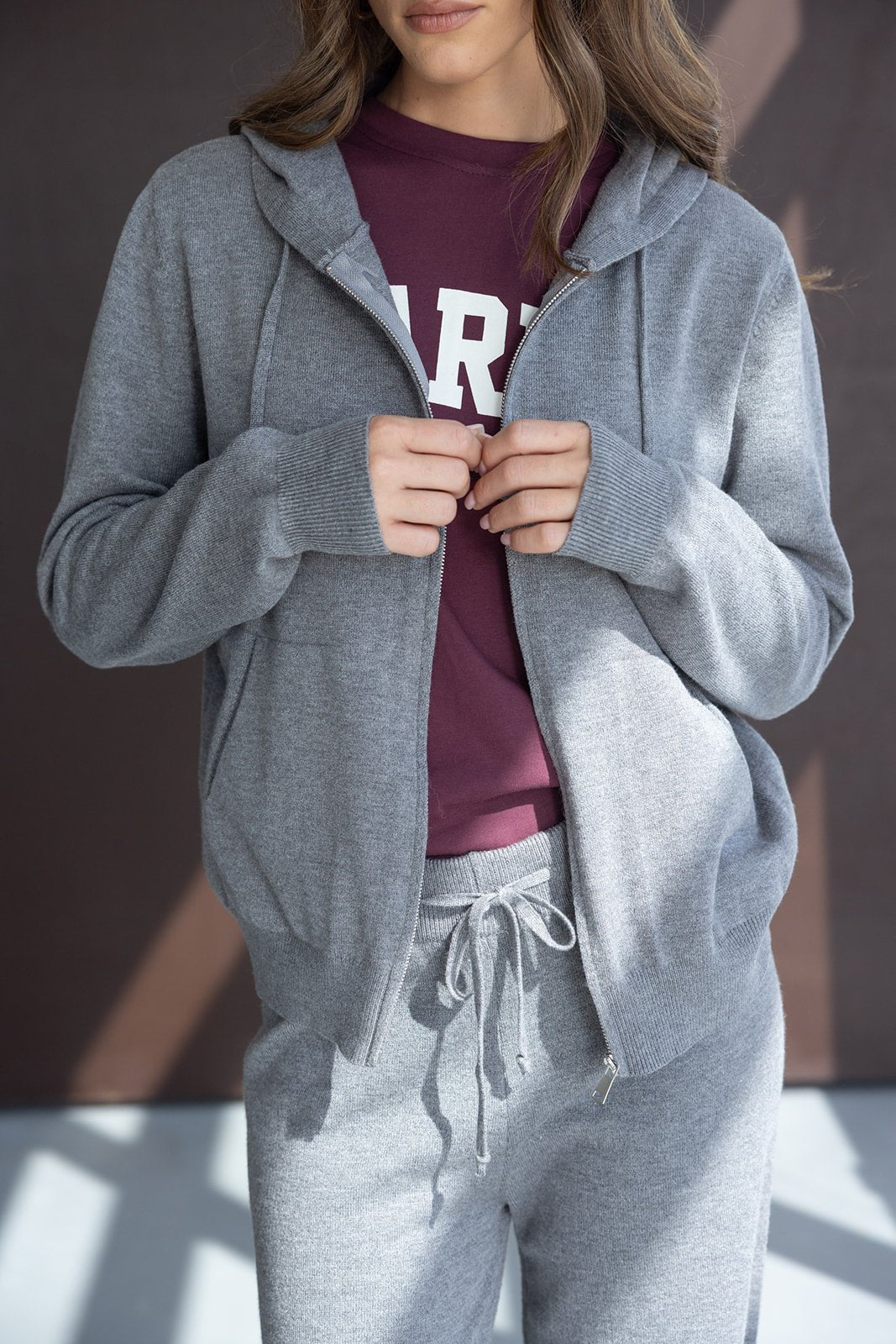 אישה לובשת סט טרנינג אפור וסווטשירט בורדו, אופנת נשים קז'ואל