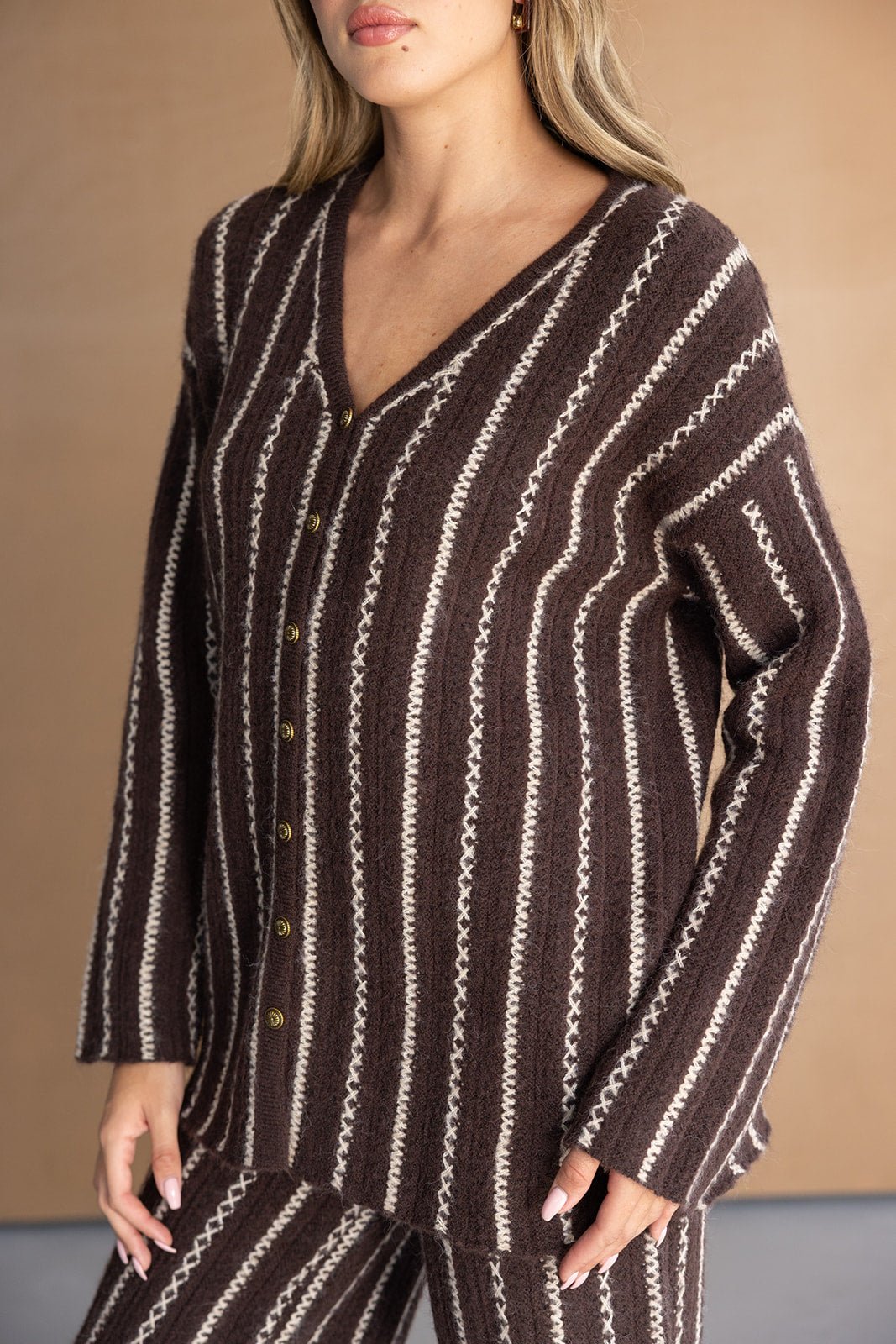 דוגמנית לובשת סריג חום עם פסים לבנים וכפתורים, אופנה לנשים בסתיו או חורף