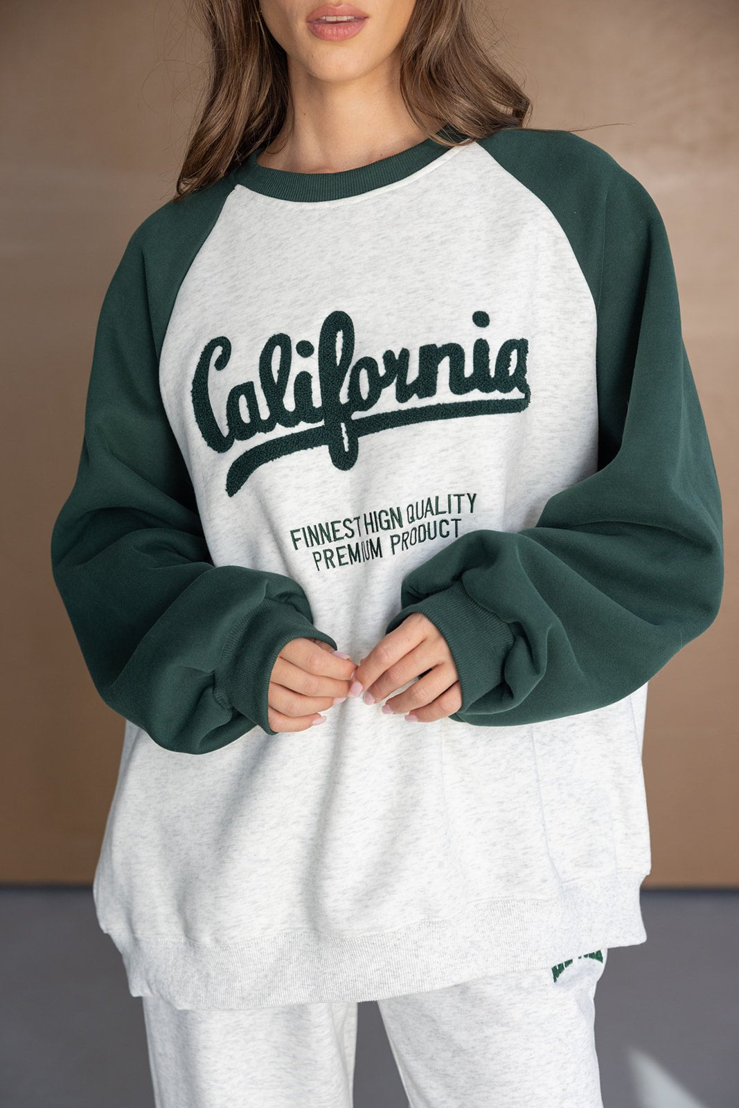 אישה לובשת סווטשירט אופנתי בצבע אפור וירוק עם כיתוב California, טרנינג לנשים