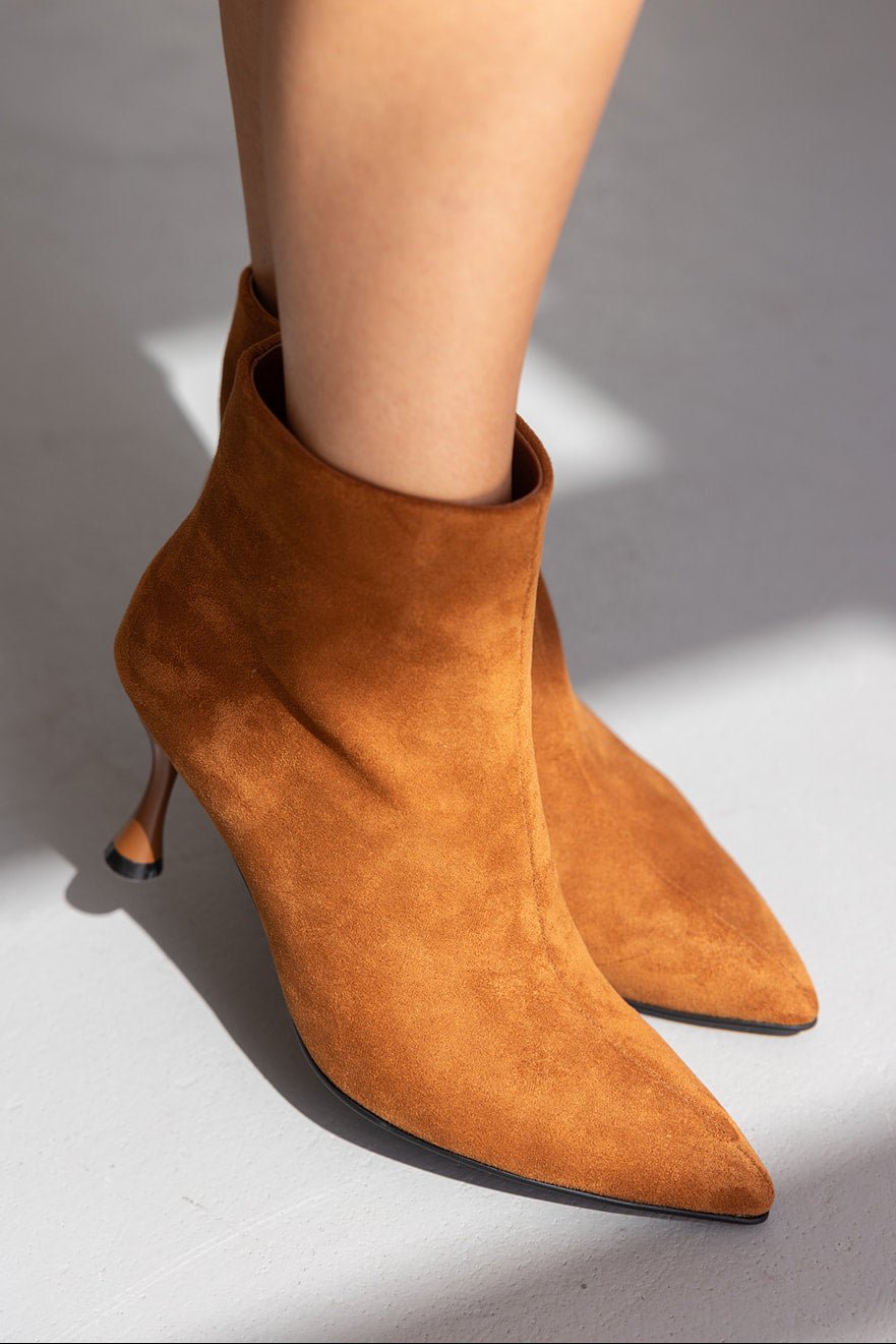 מגפוני עקב קטיפה חומים לנשים עם חרטום מחודד, צילום אופנה ברקע בהיר