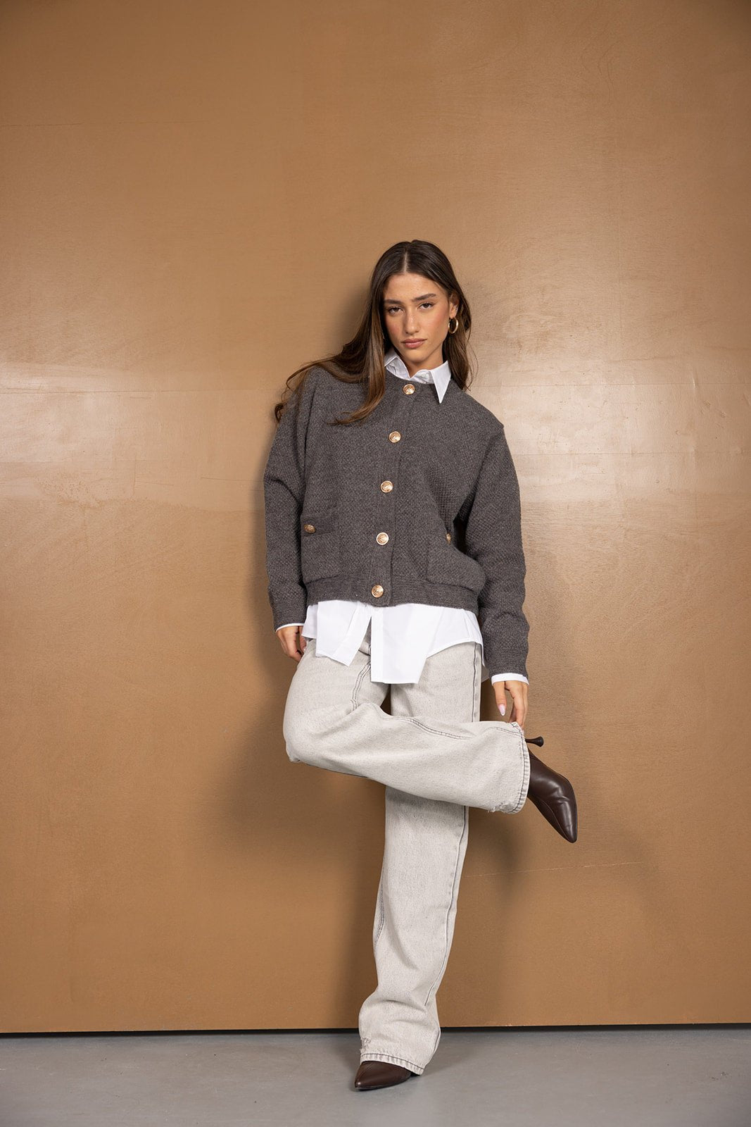 דוגמנית לובשת קרדיגן אפור עם כפתורים, חולצה לבנה ומכנסי ג'ינס רחבים, אופנה לנשים