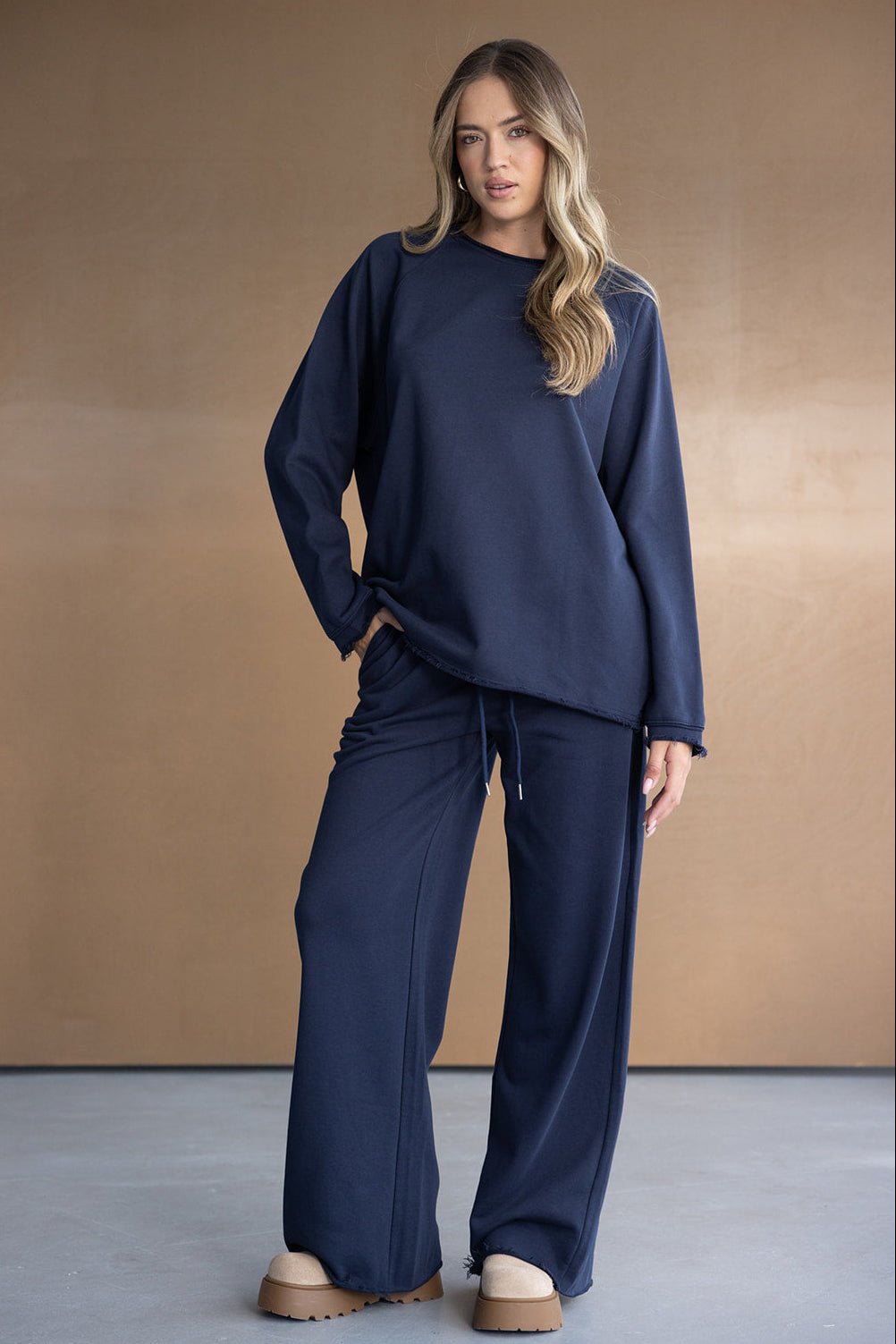 דוגמנית לובשת סט טרנינג נשים כחול כהה עם מכנס רחב וסווטשרט, אופנה עדכנית לנשים