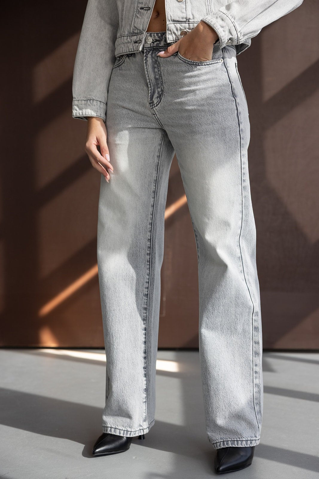 ג'ינס נשים בגזרה ישרה בצבע אפור בהיר, משולב עם נעלי עקב שחורות, אופנת רחוב עדכנית