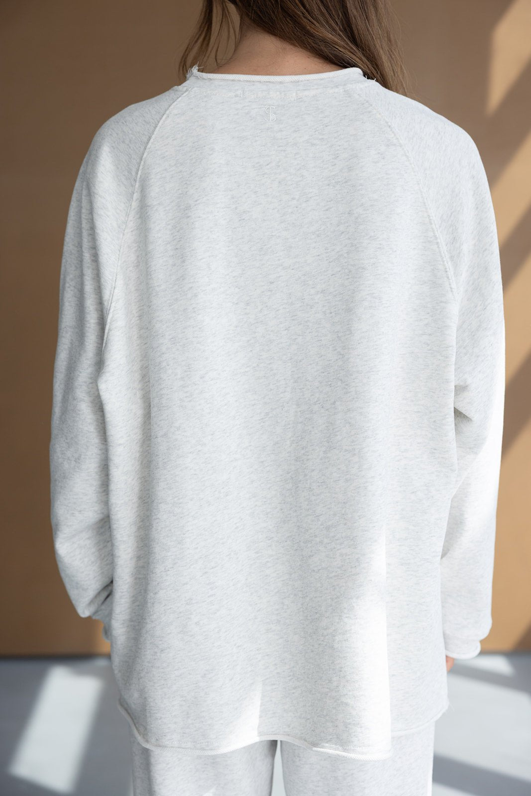 חולצת טרנינג נשים אפורה ארוכה מבד נעים, מצולמת מאחור, אופנה לנערות