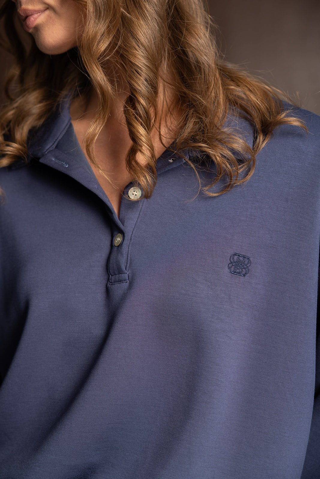 חולצת פולו נשים כחולה עם רקמת לוגו, כפתורים וצווארון אופנתי, שיער מתולתל