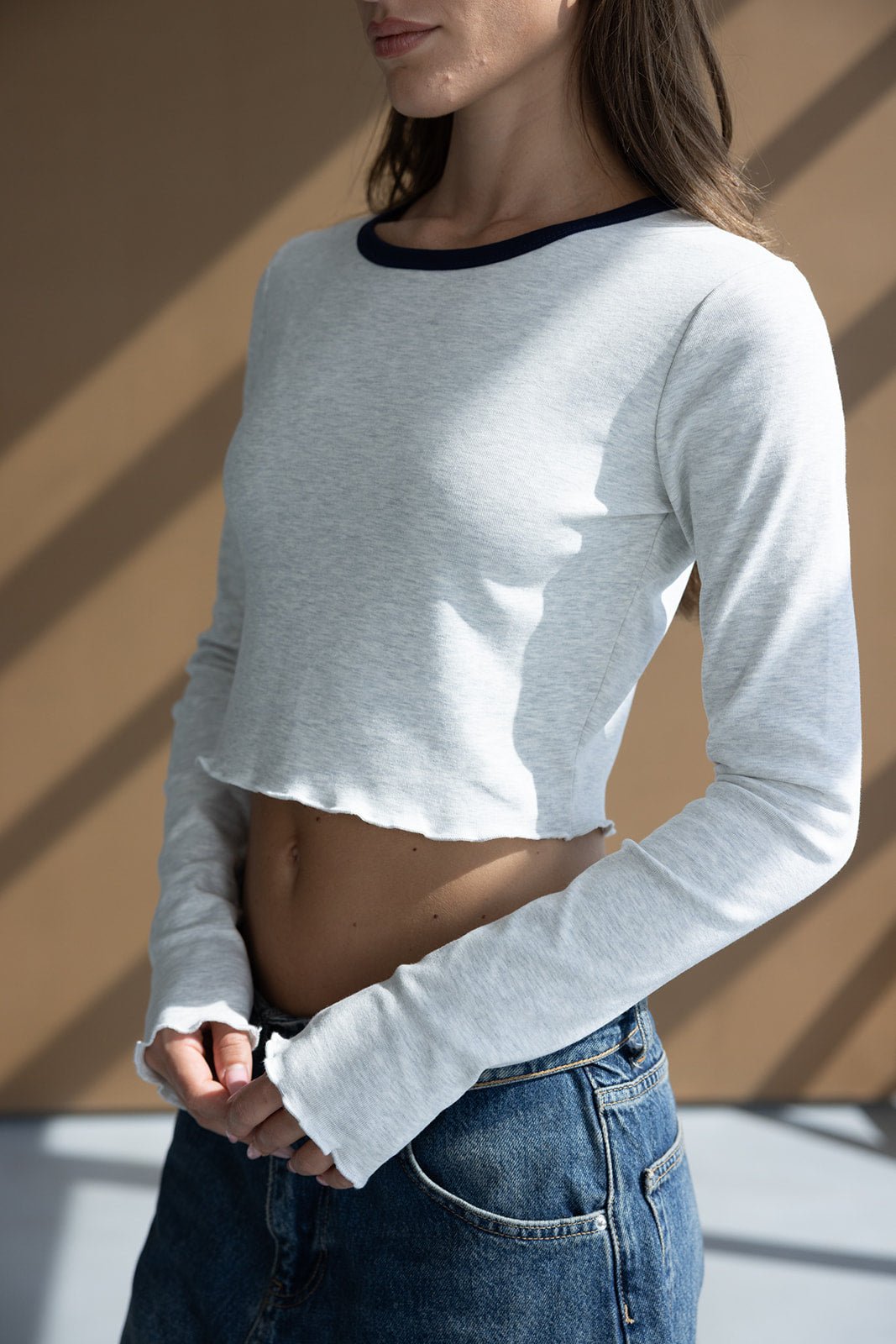 חולצת קרופ שרוול ארוך בצבע אפור עם גזרת סיומת גלי וסקיני, משולבת עם ג'ינס כחול לנשים אופנתיות