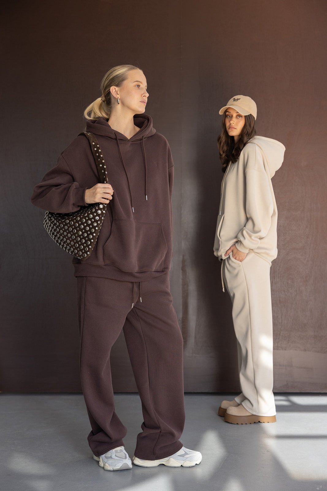 שתי נשים לובשות סט קפוצ'ון ומכנסי טרנינג אופנתי בגווני חום ובז', לוק יומיומי מודרני