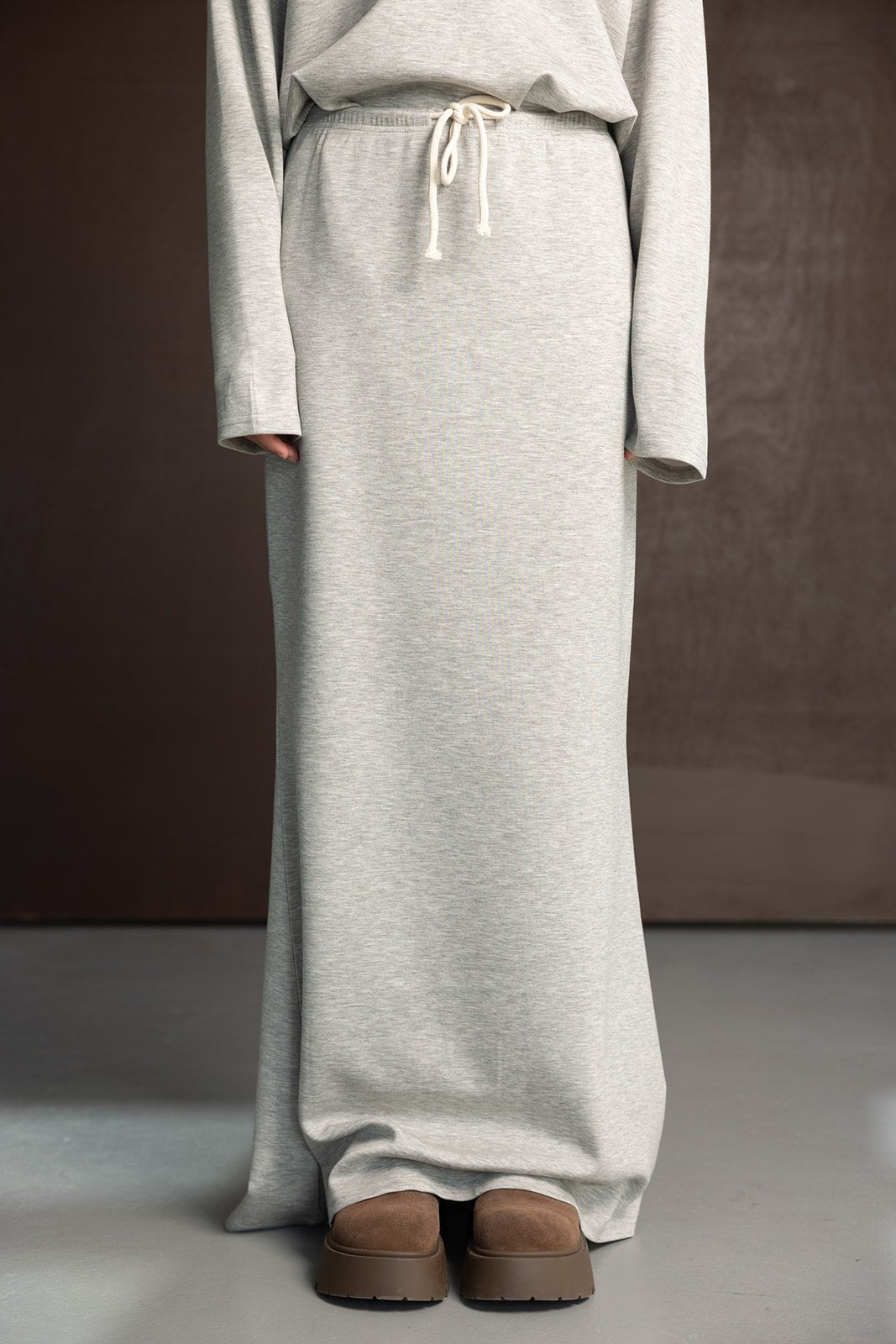 חצאית לנשים בצבע אפור בהיר מבד רך עם גומי וקשירה, נעלי פלטפורמה חומות