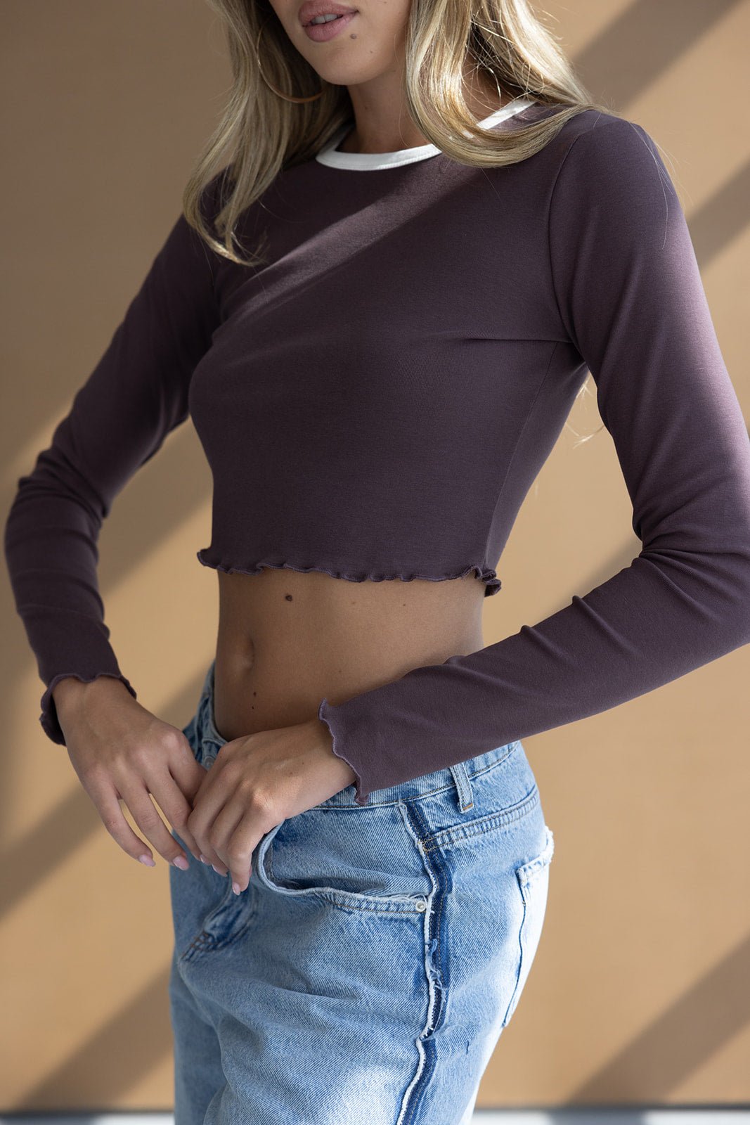 חולצת קרופ שרוול ארוך בצבע סגול כהה עם גימור לבן, ג'ינס משופשף, אופנת נשים צעירה