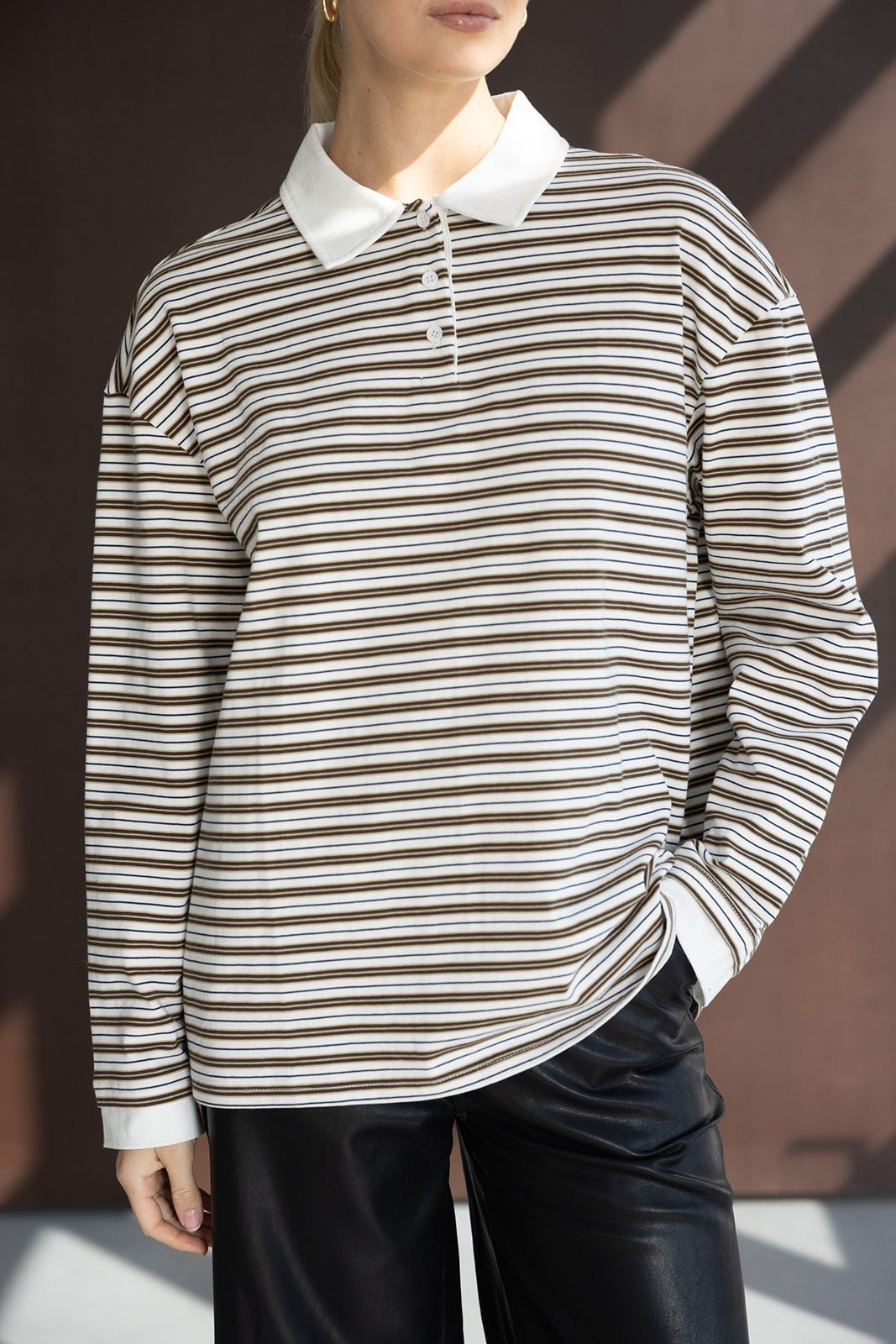 חולצת פולו ארוכה פסים חומים ולבנים לנשים, צווארון לבן, נלבשת עם מכנס עור שחור