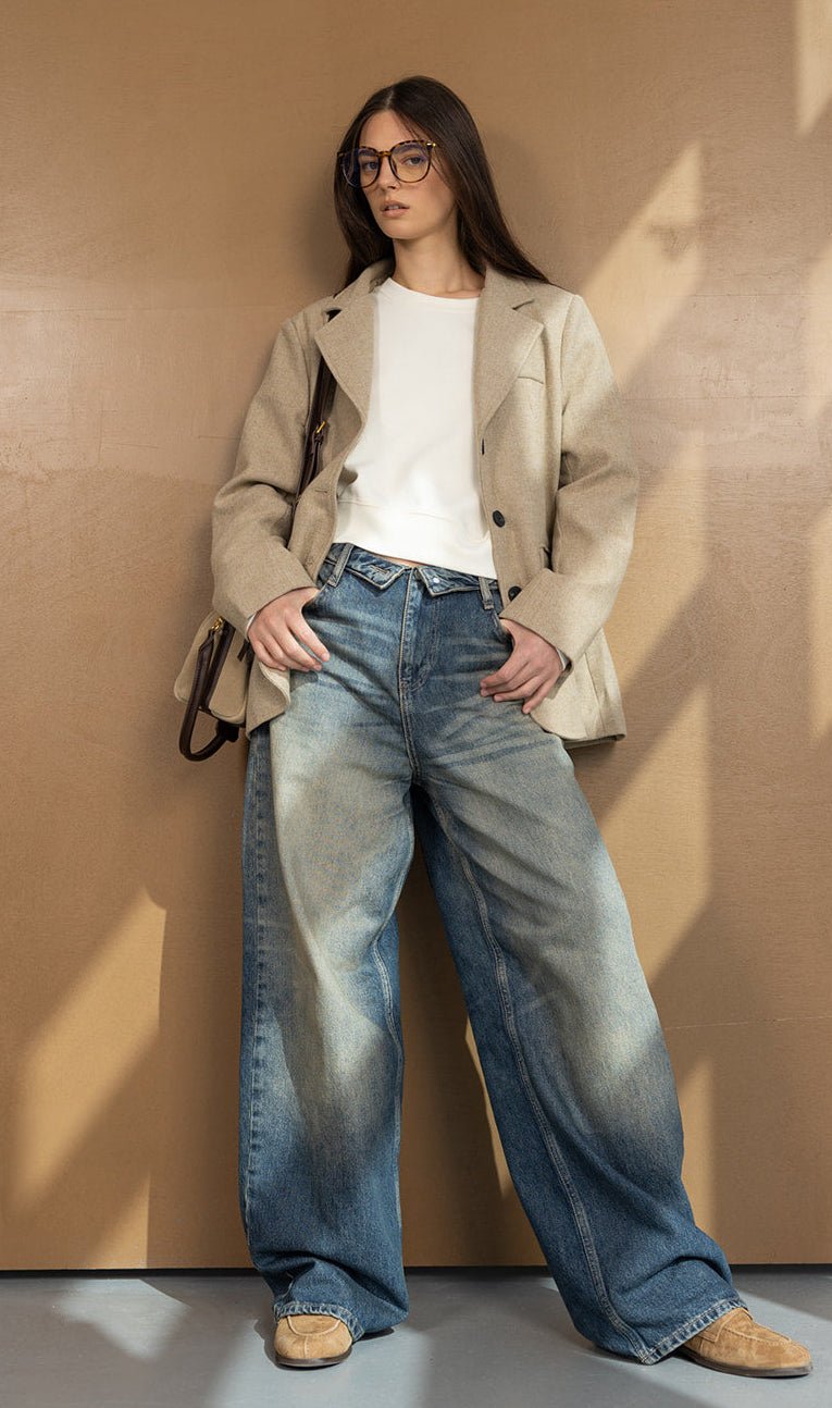 אישה צעירה עם ג'ינס רחב בהד washed, חולצה לבנה, בלייזר בז' ומשקפיים אופנתיים, לוק קז'ואל לנשים