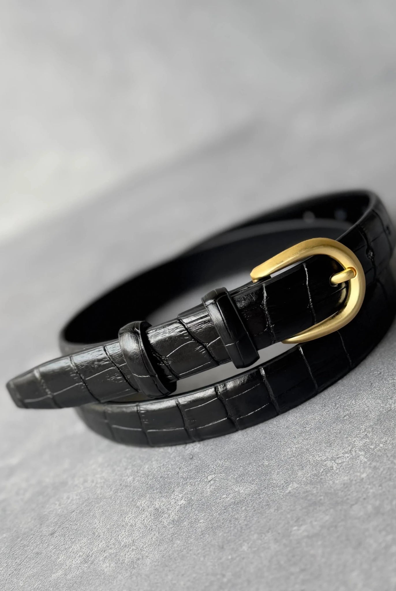 חגורת נשים אופנתית דמוי עור שחור עם אבזם זהב בעיצוב קלאסי, על רקע אפור