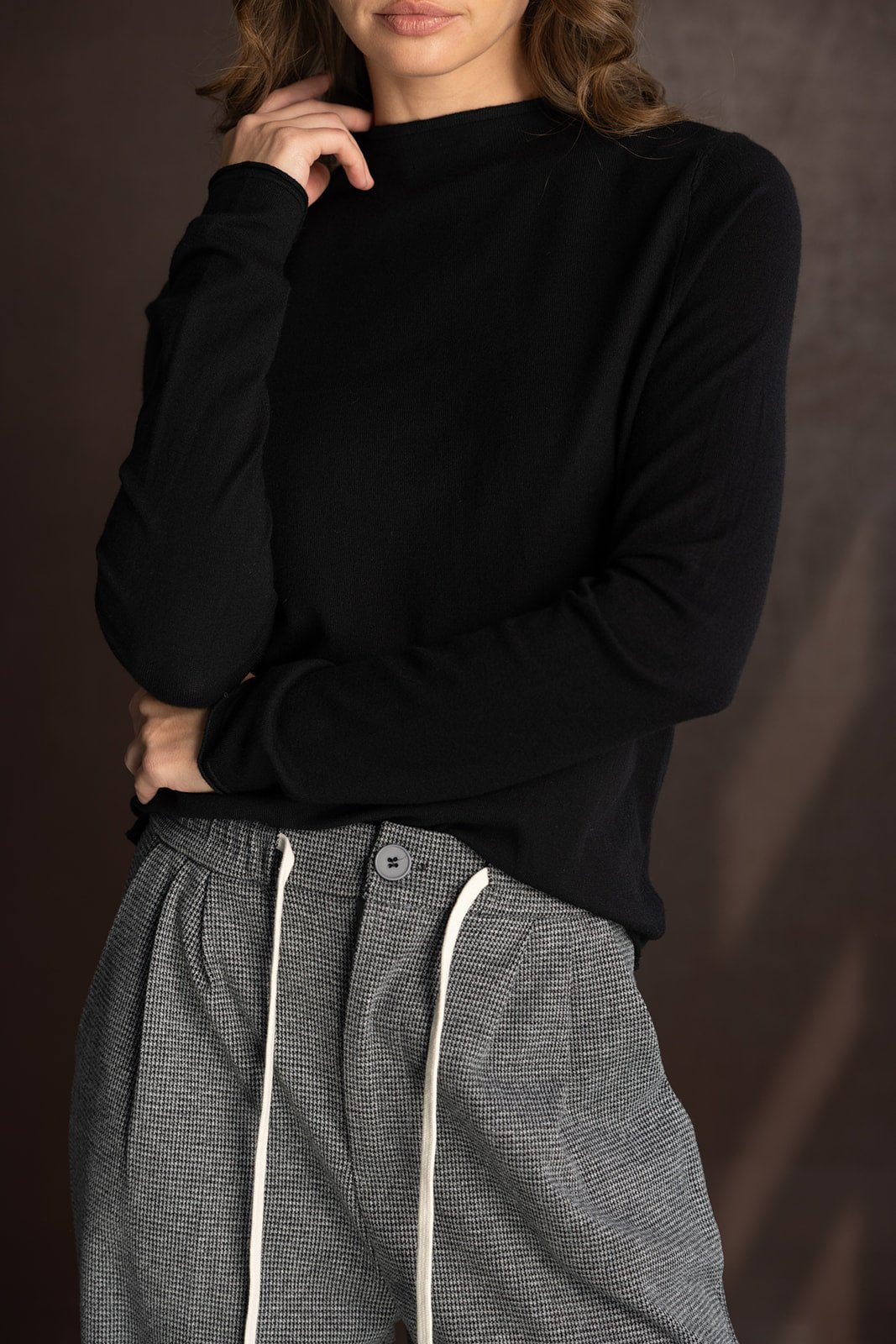 דוגמנית עם סווטשרט שחור חלק ומכנסיים אפורים גבוהים עם שרוך לבן, אופנת נשים חורף