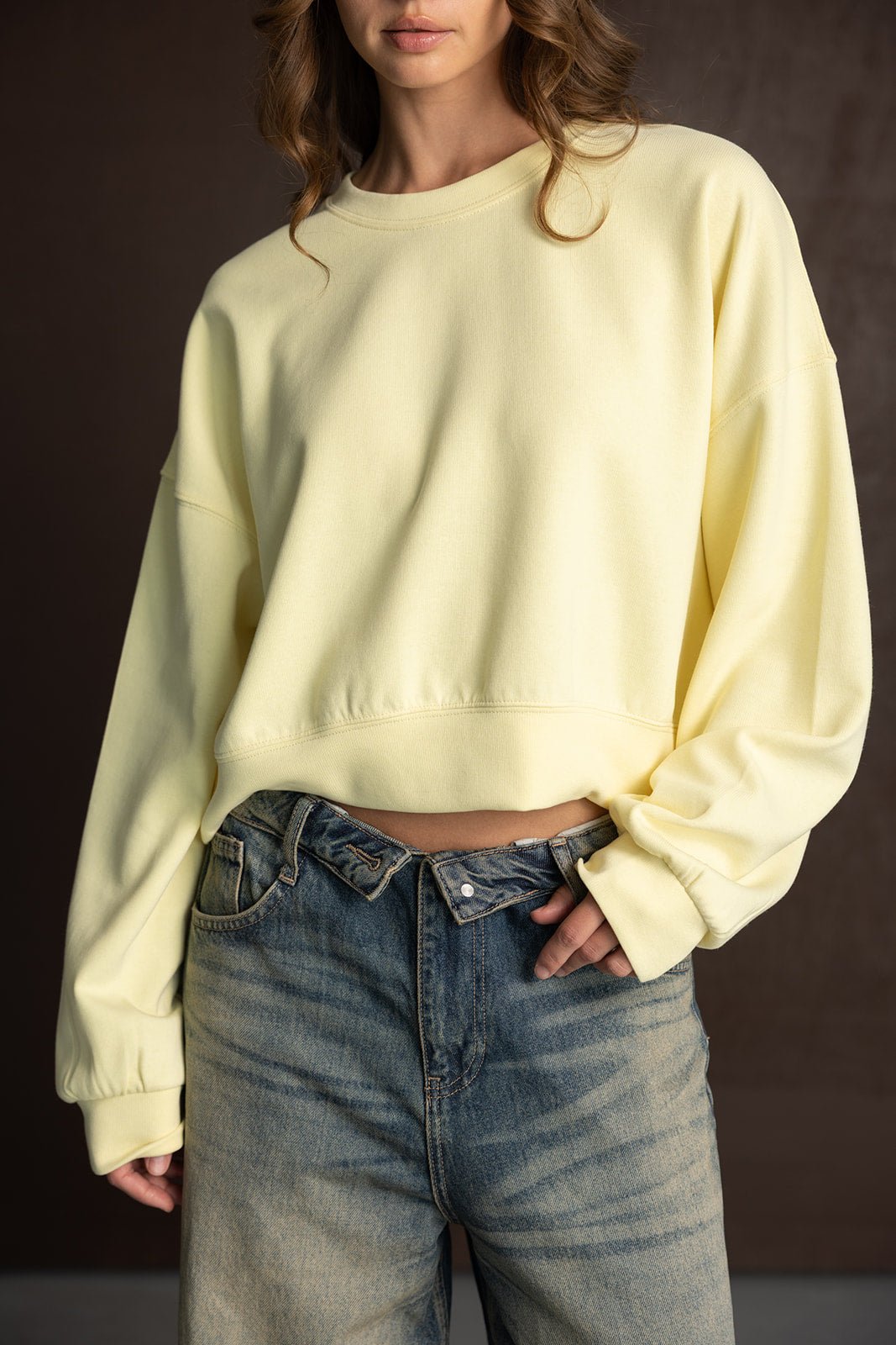 דוגמנית לובשת סווטשירט צהוב אופנתי ומכנסי ג'ינס גבוהים לנשים טרנדיות