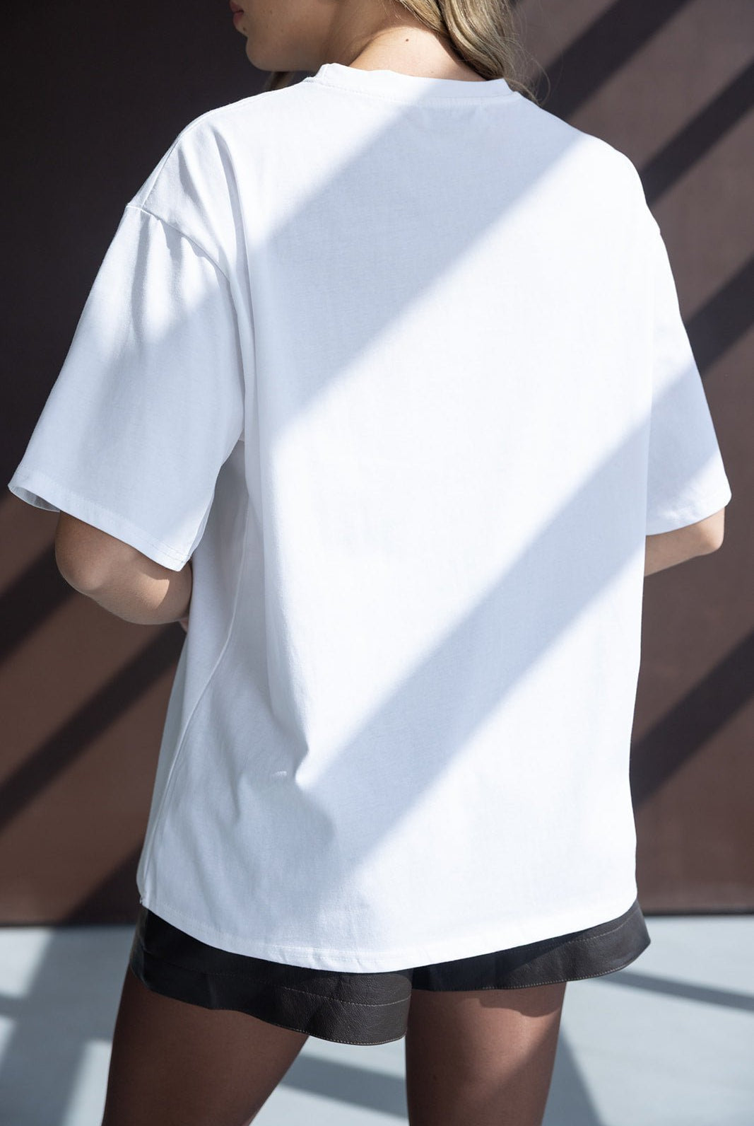 אישה לובשת טי שירט לבנה קצרה ומכנסיים שחורים, אופנה לנשים צעירות