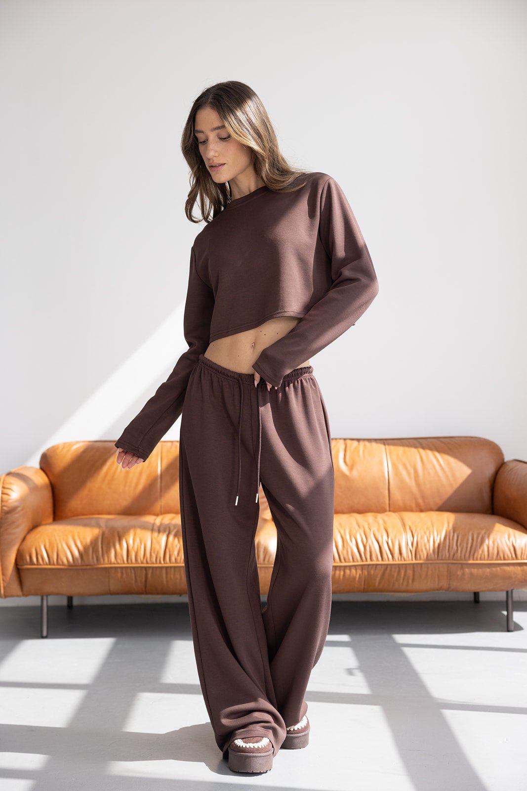 דוגמנית לובשת סט טרנינג חום לנשים, חולצה בטן ומכנסיים רחבים, אופנת חורף נוחה וביתית