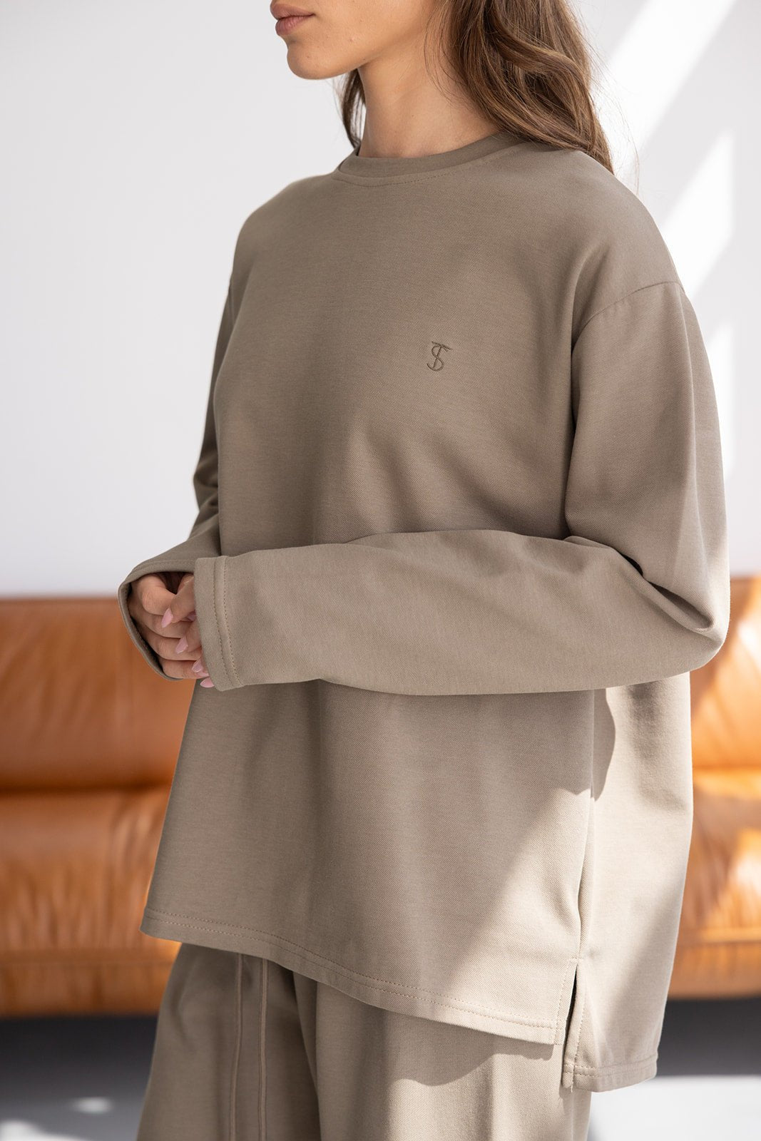 דוגמנית לובשת חולצת טריקו נשים בצבע בז' עם שרוולים ארוכים, לוק קז'ואל לבית או ליום יום