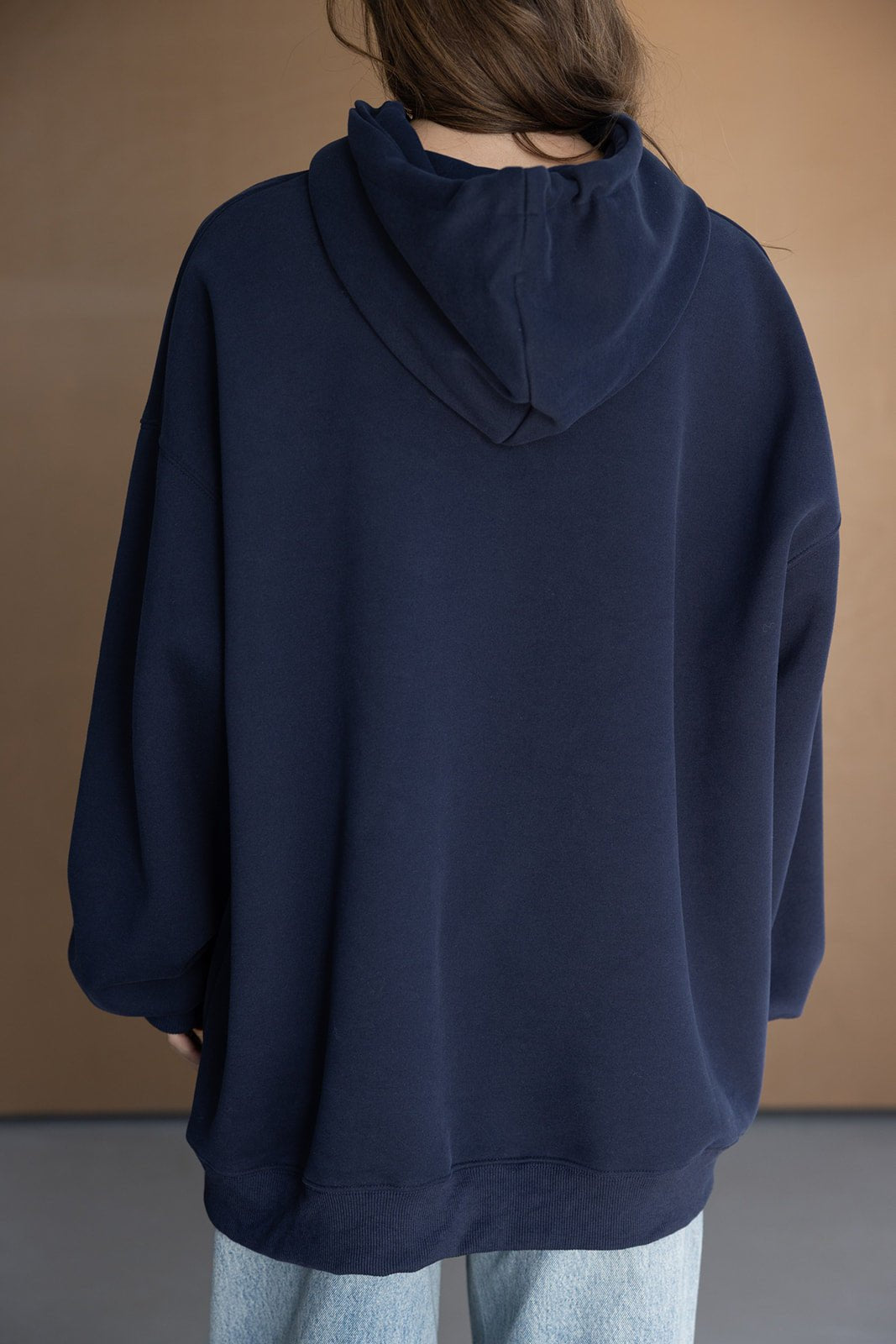 אישה בלבוש יומיומי עם קפוצ'ון כחול כהה ומכנסי ג'ינס, צילום מהגב