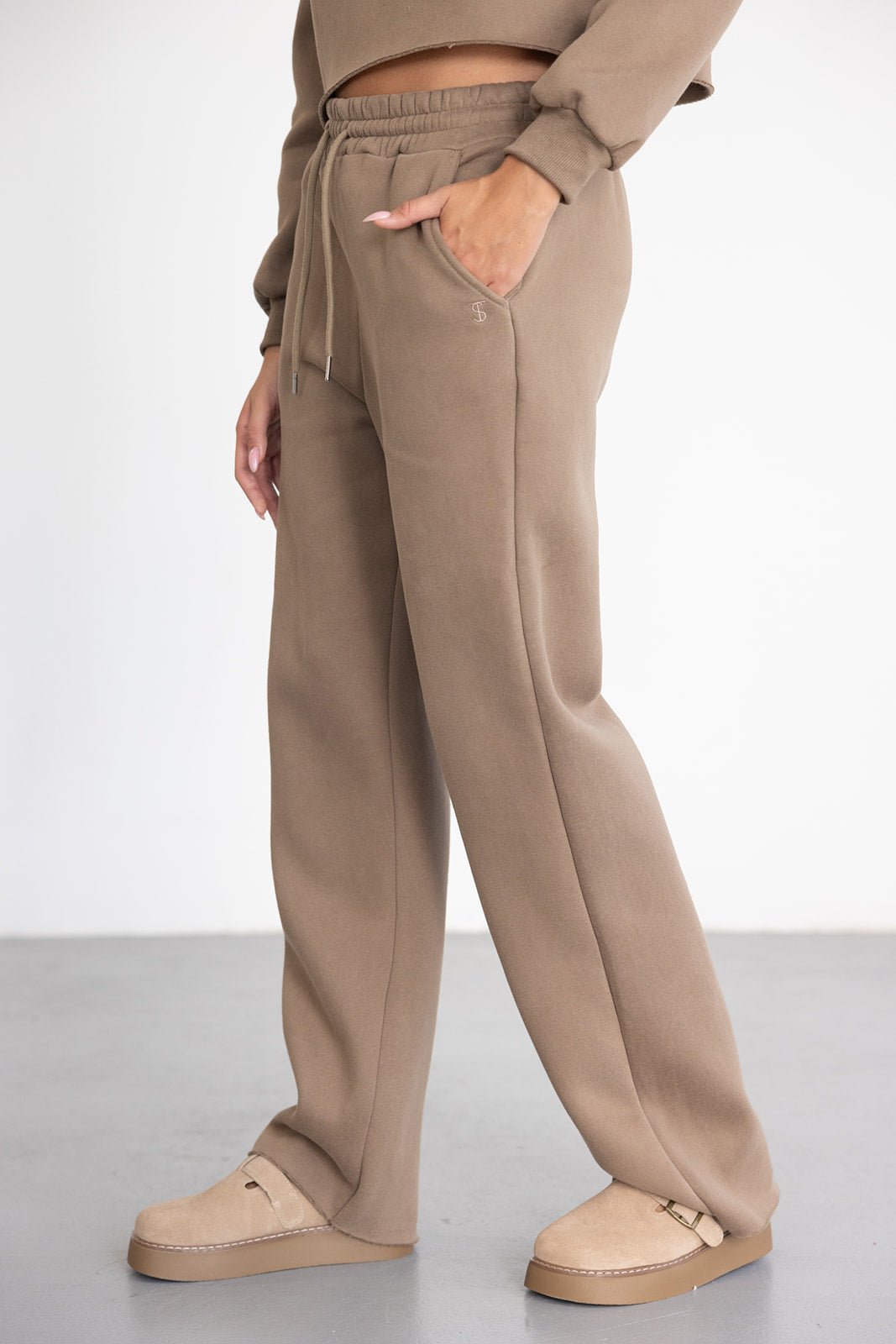 מכנסי טרנינג נשים בצבע חום בהיר עם גומי במותן וכיסים, נעלי בית בצבע תואם