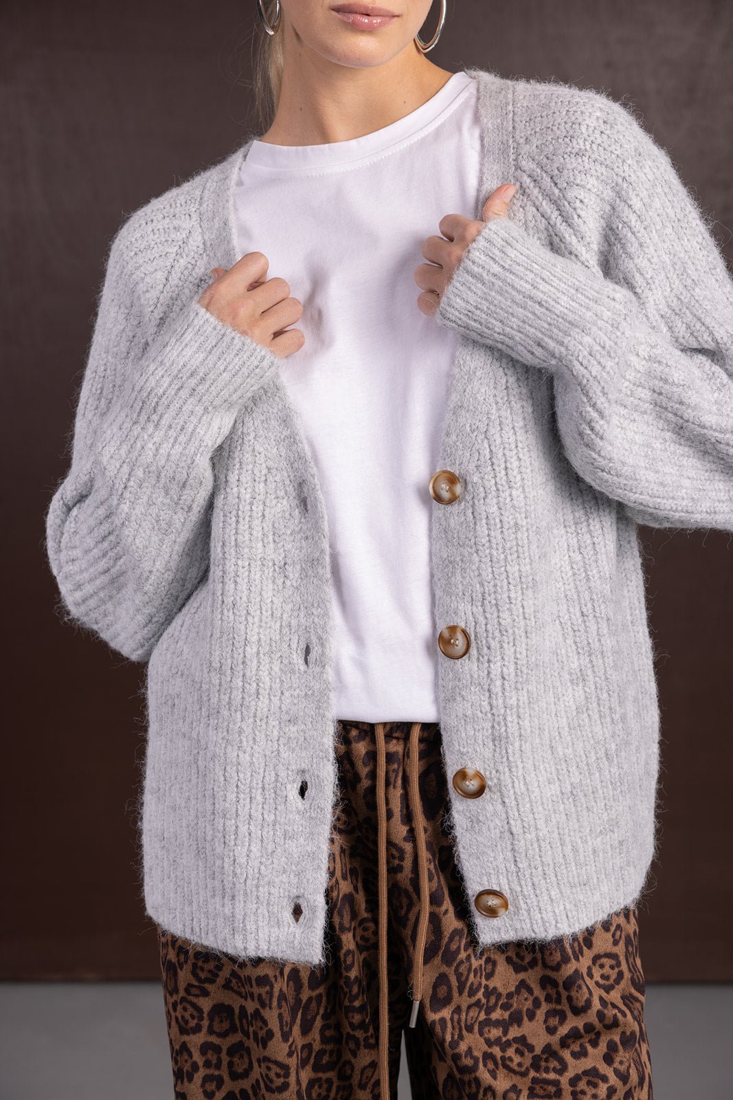 קרדיגן אפור עם כפתורים חומים, חולצה לבנה ומכנסי הדפס מנומר לאופנת נשים