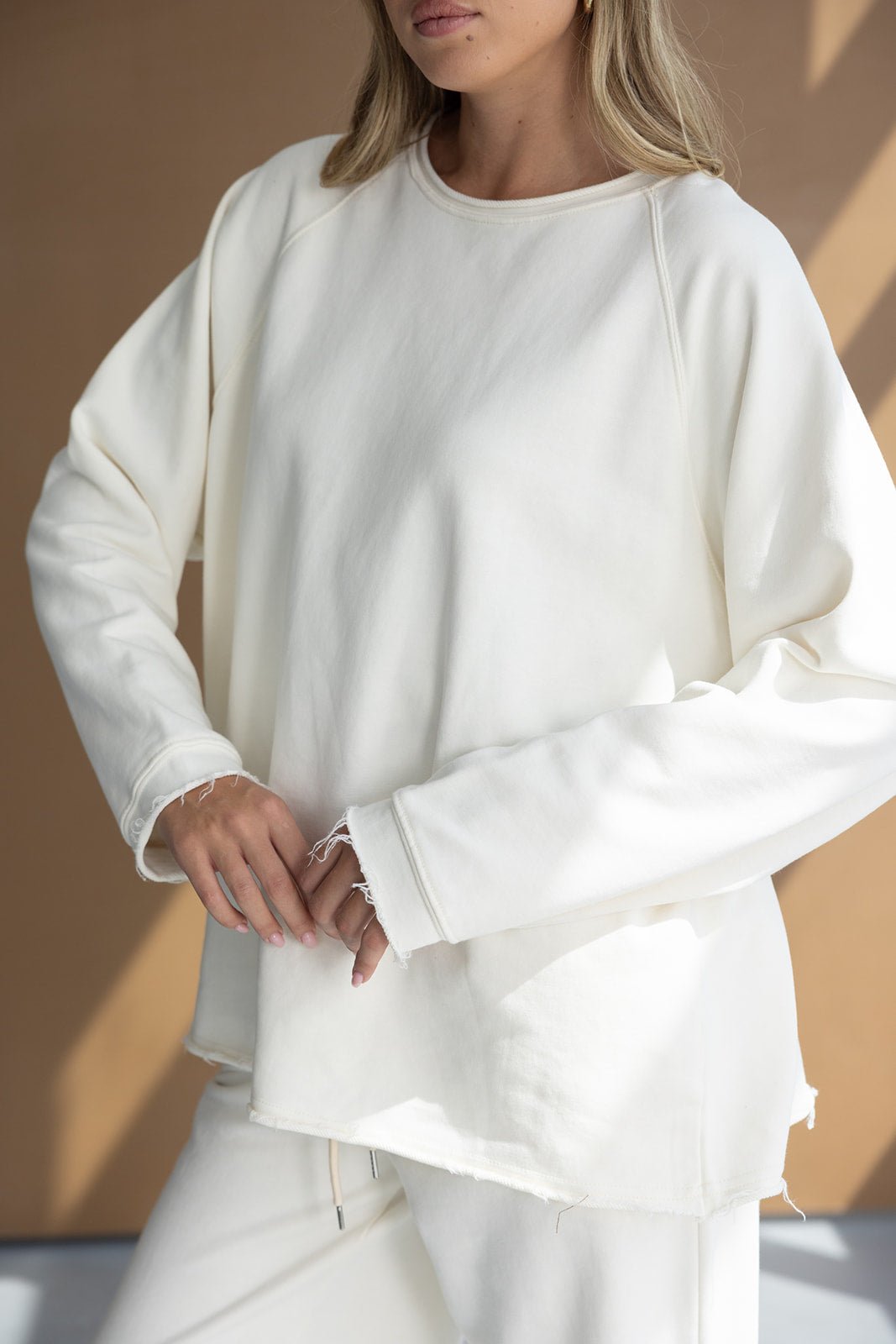 דוגמנית עם סט בגדי נשים טרנדי בצבע שמנת, סווטשירט ארוך ומכנסיים תואמים