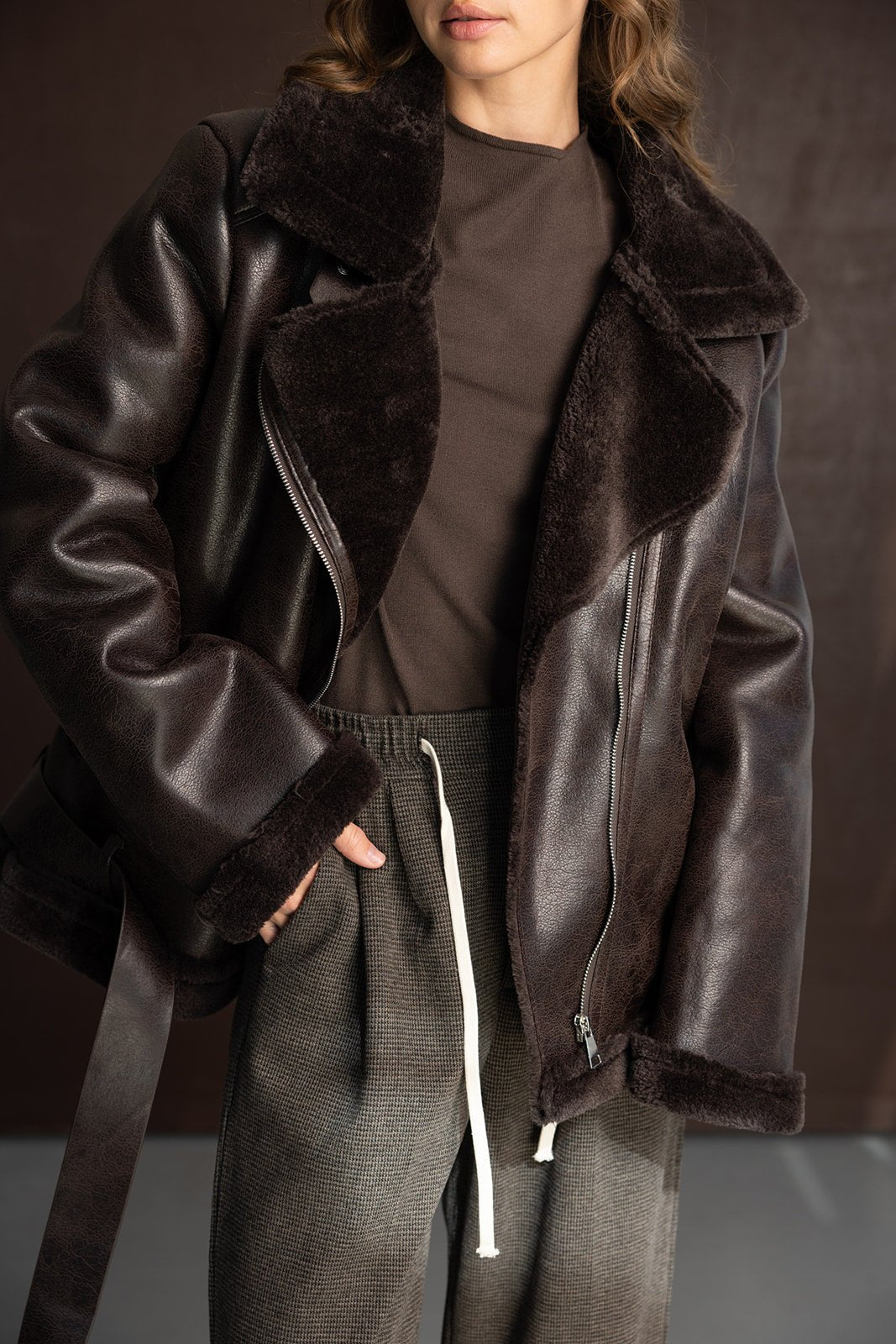 אישה לובשת מעיל עור חום עם פרווה וביגוד חורף אופנתי לנשים